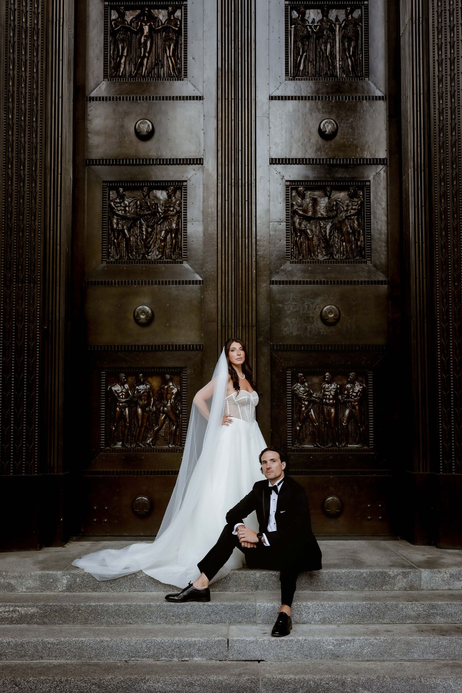 Artistic wedding portraits taken against ornate wooden doors with decorative panels.
