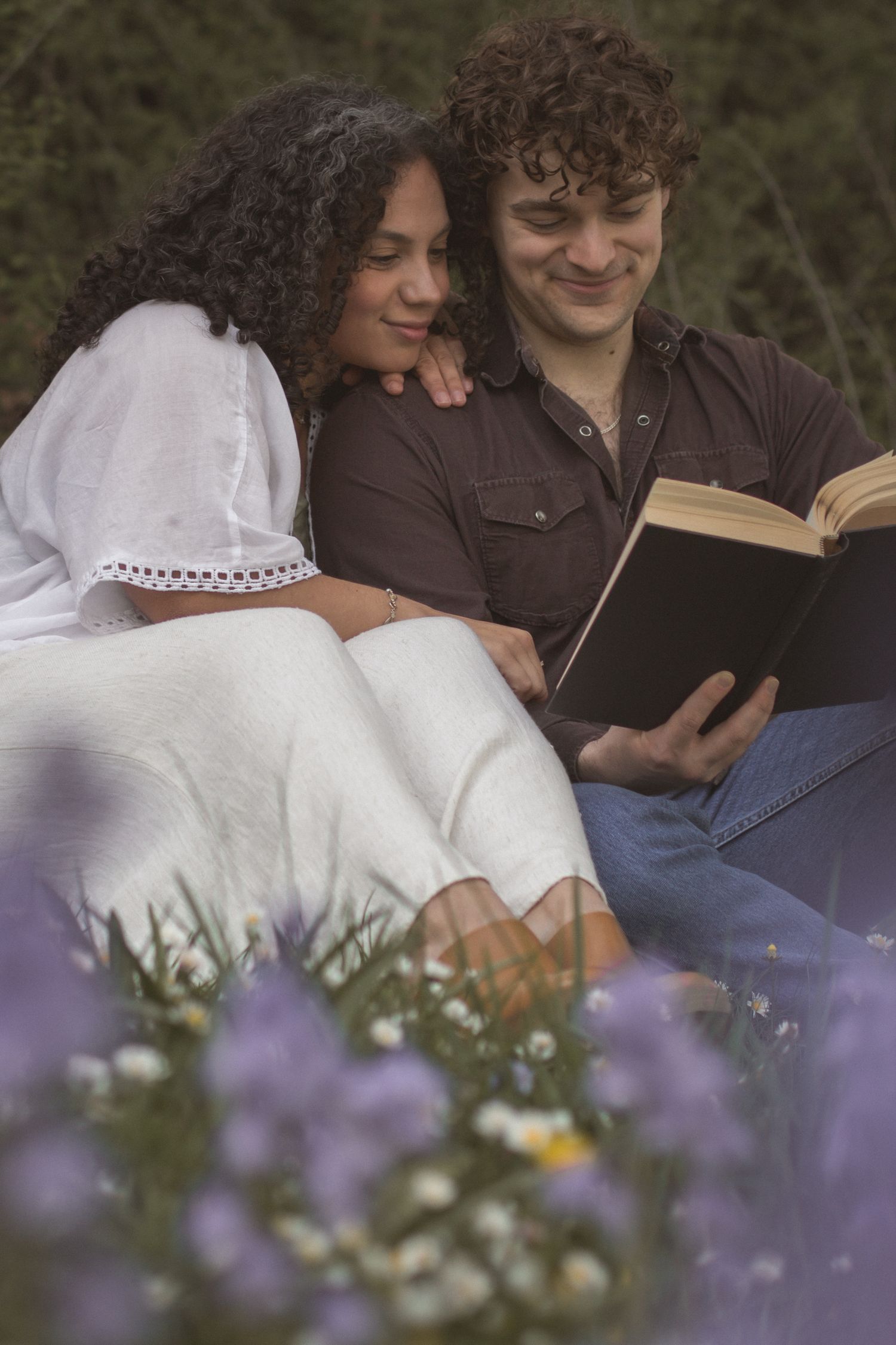 cinematic Photo of couple reading in grass with purple flowers in Seattle, Washington.