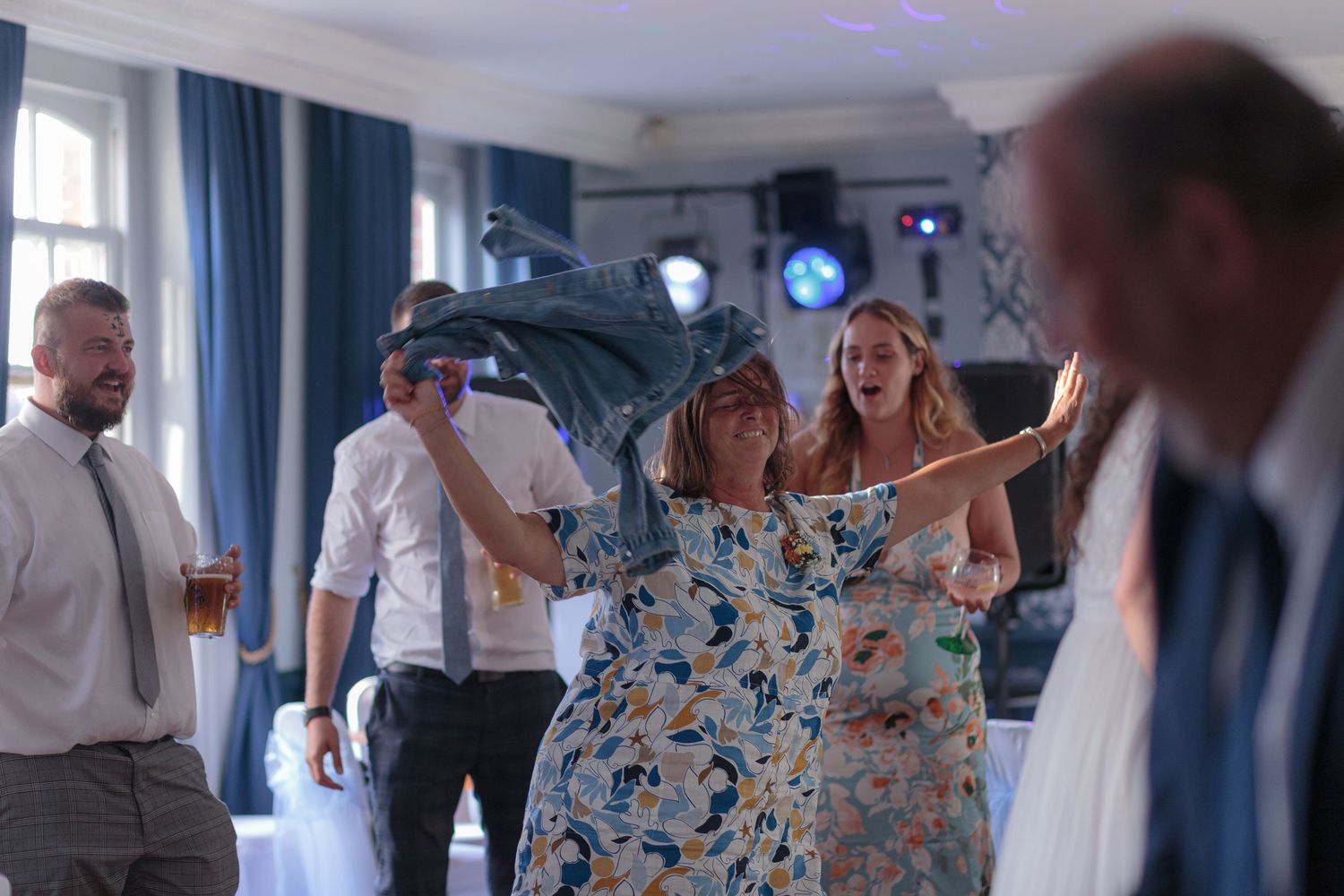 A woman in the centre of a dance circle, swinging her denim jacket around her head - completely lost in the music.