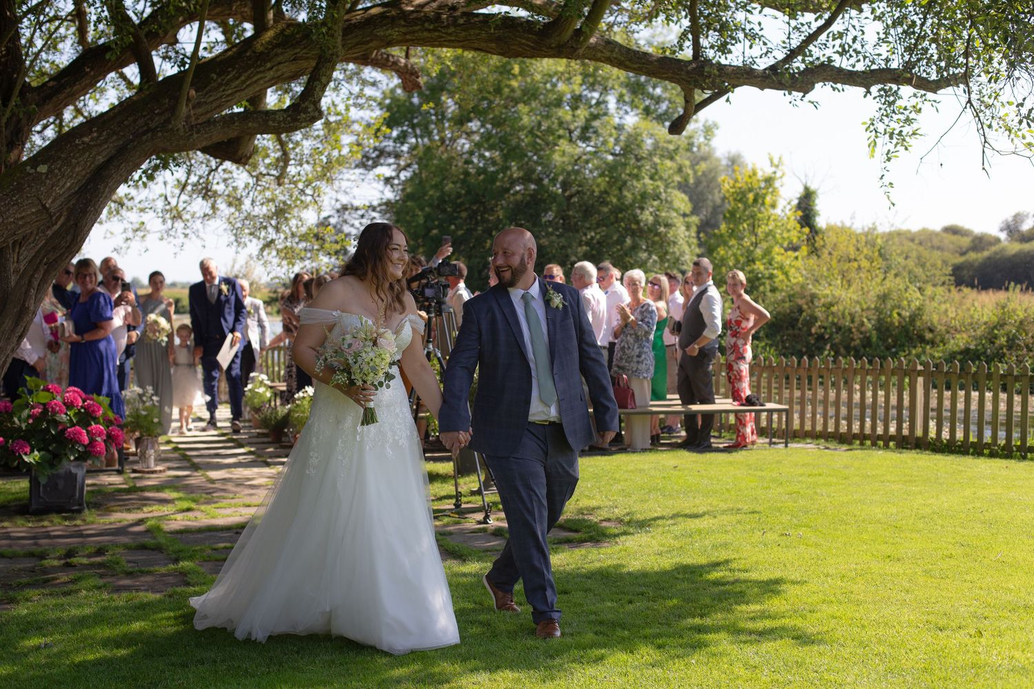 Bride and Groom walk back down the aisle together, their guests cheering behind them