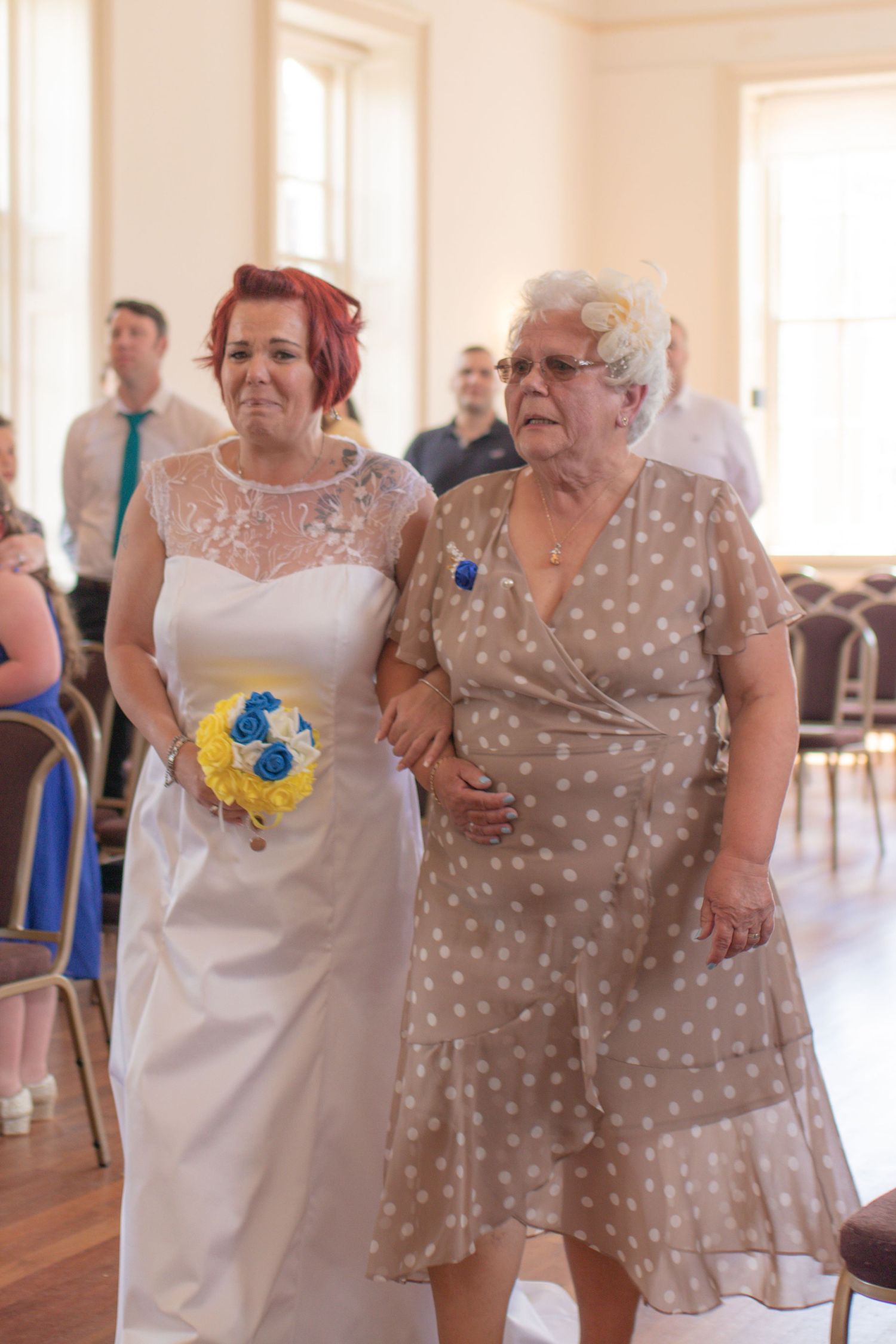Emotional bride and her mother walking down the aisle at the start of wedding ceremony at Poole Guildhall.