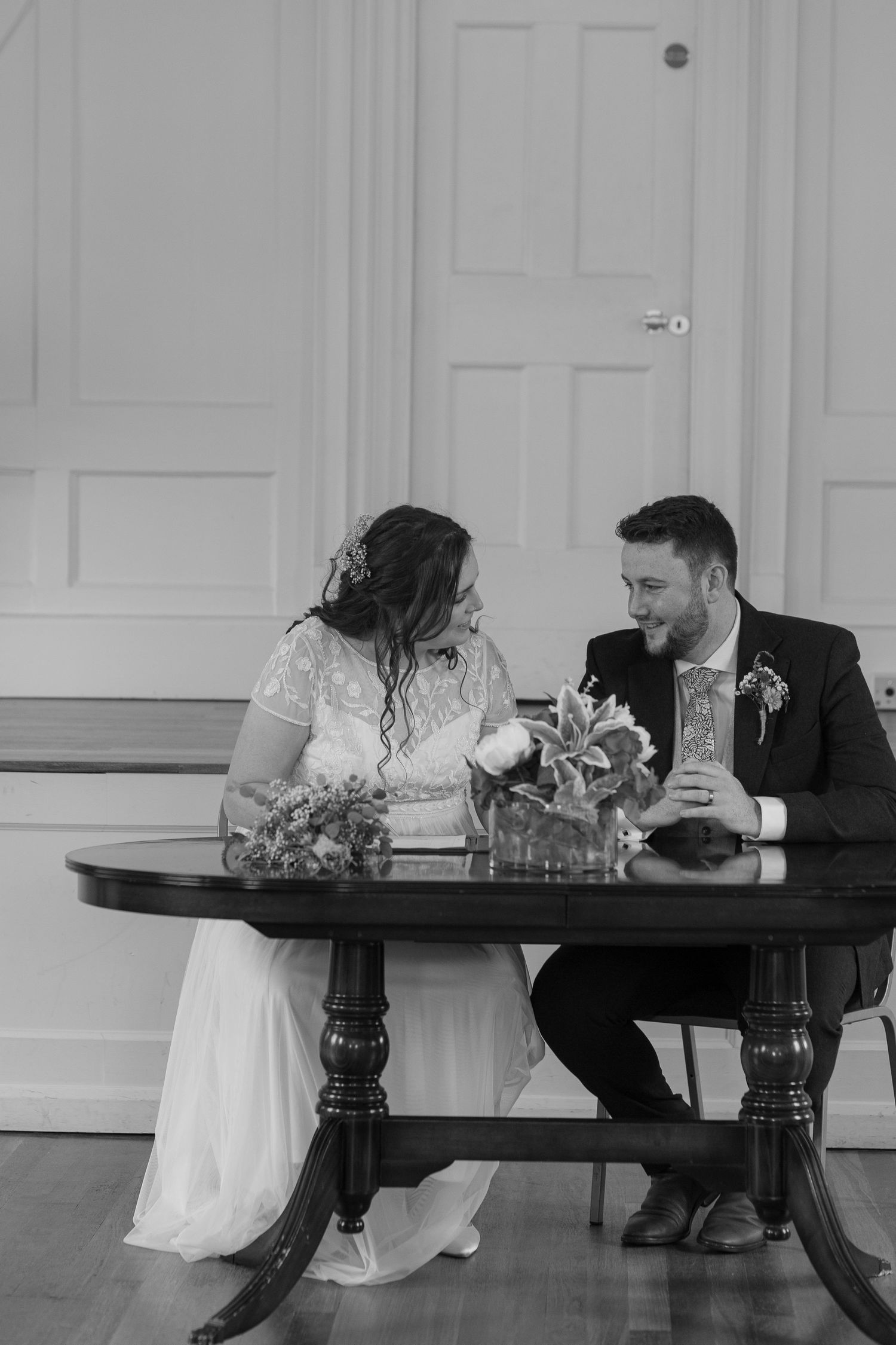 Bride and Groom talking quietly amongst themselves, sitting at a table ready to sign their marriage license