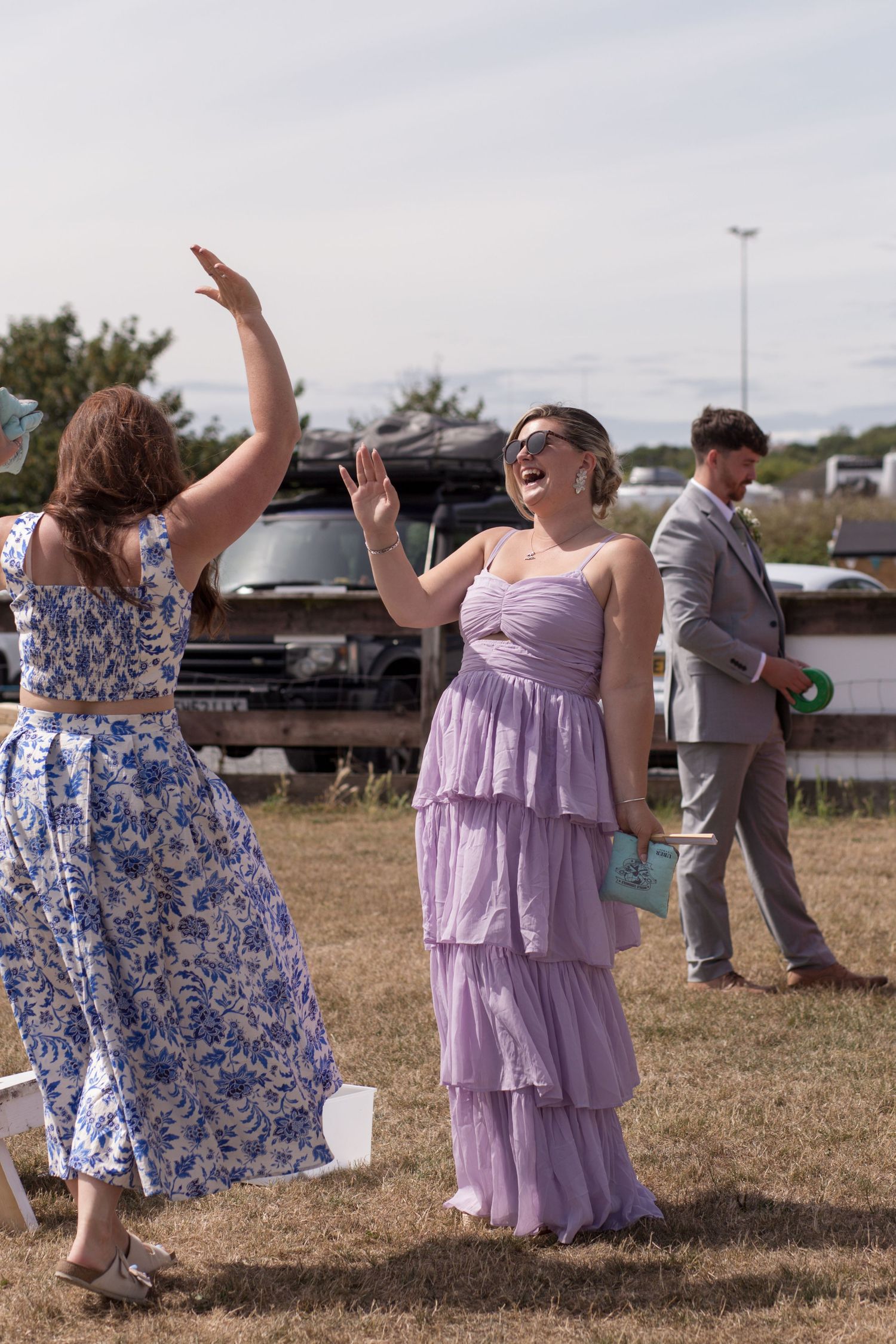 Two female wedding guest laughing and celebrating after beating their partners at a game of bean bag toss