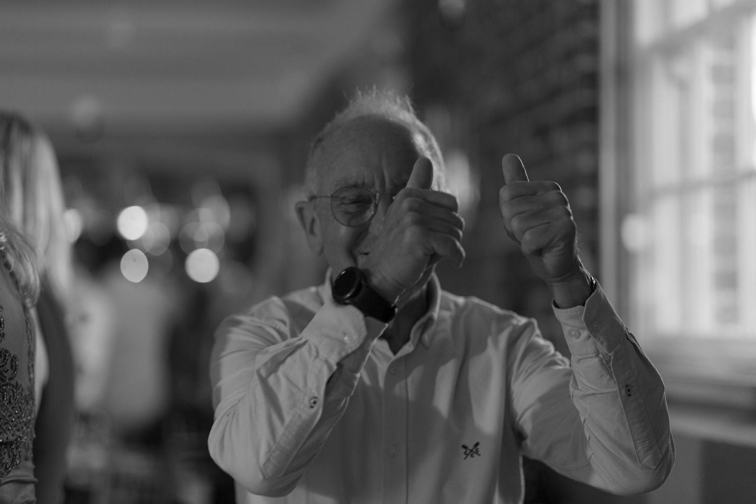 An elderly man gives the camera two thumb up as he makes his way onto the dance floor
