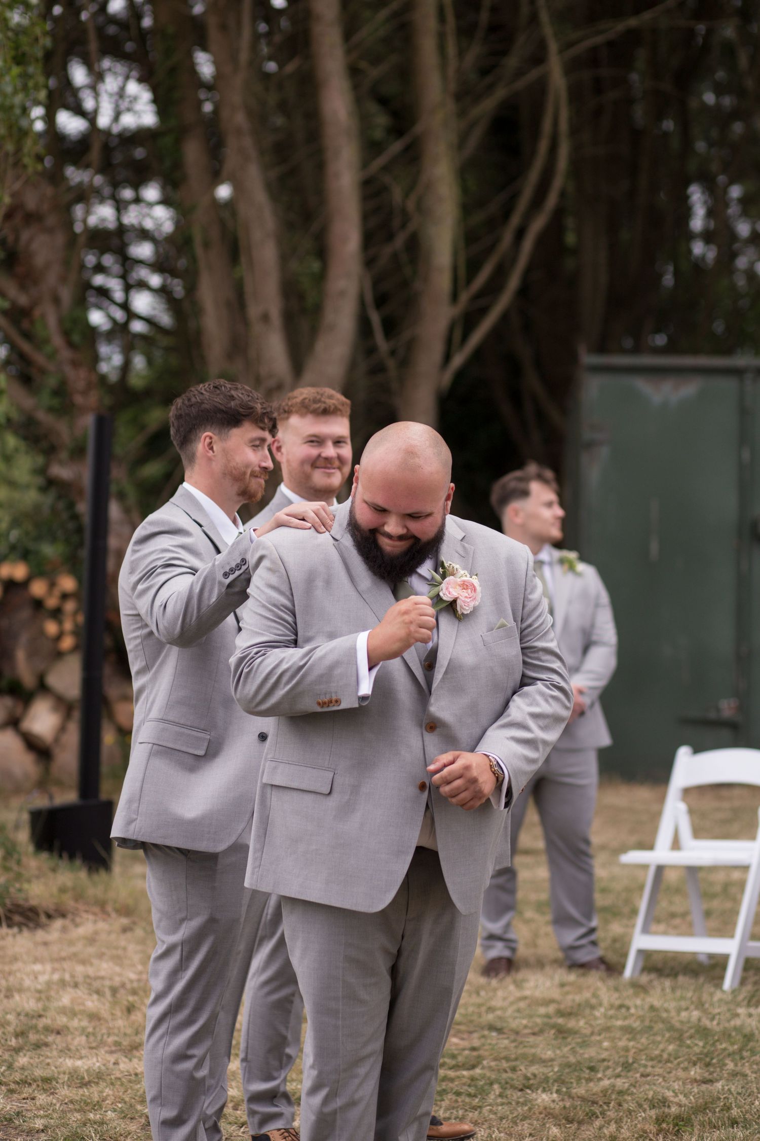 Groom sheds a tear at the front of the ceremony watching his bride walk down the aisle, and his best man gives him a pat on the shoulder