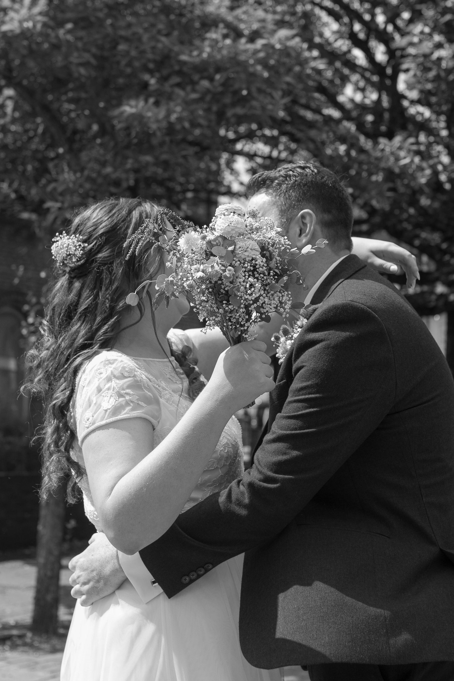 Bride and Groom share a kiss, hidden behind the bride's bouquet