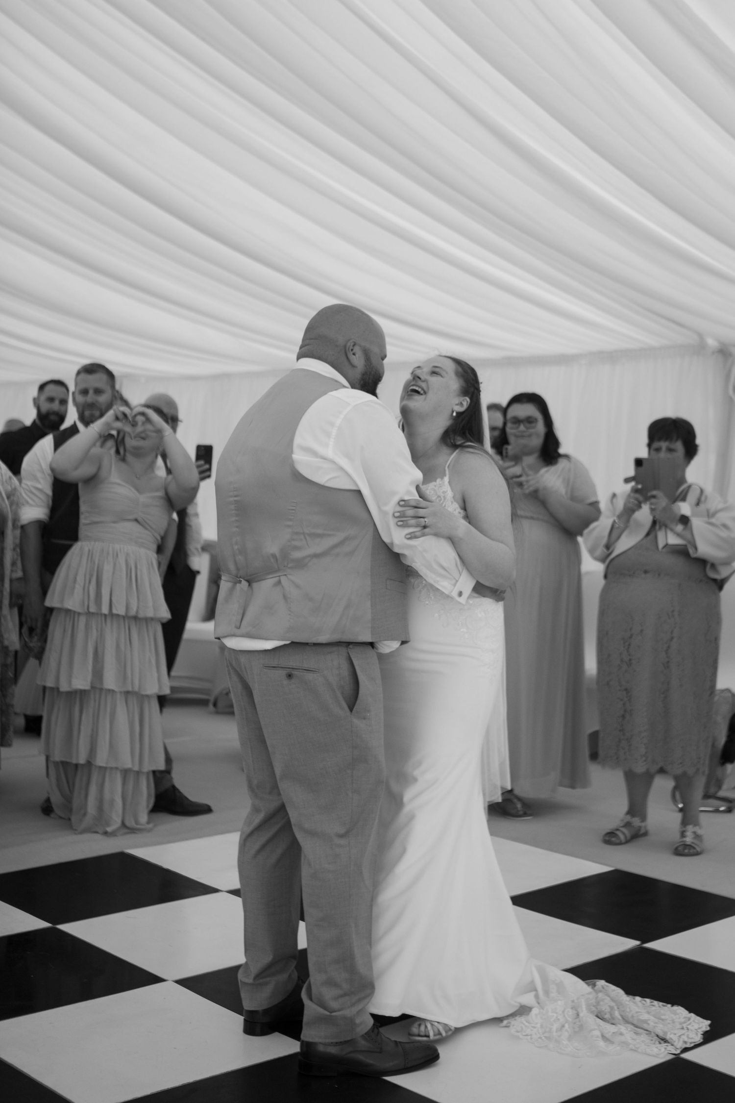 Bride and Groom laugh together in the middle of their first dance.
