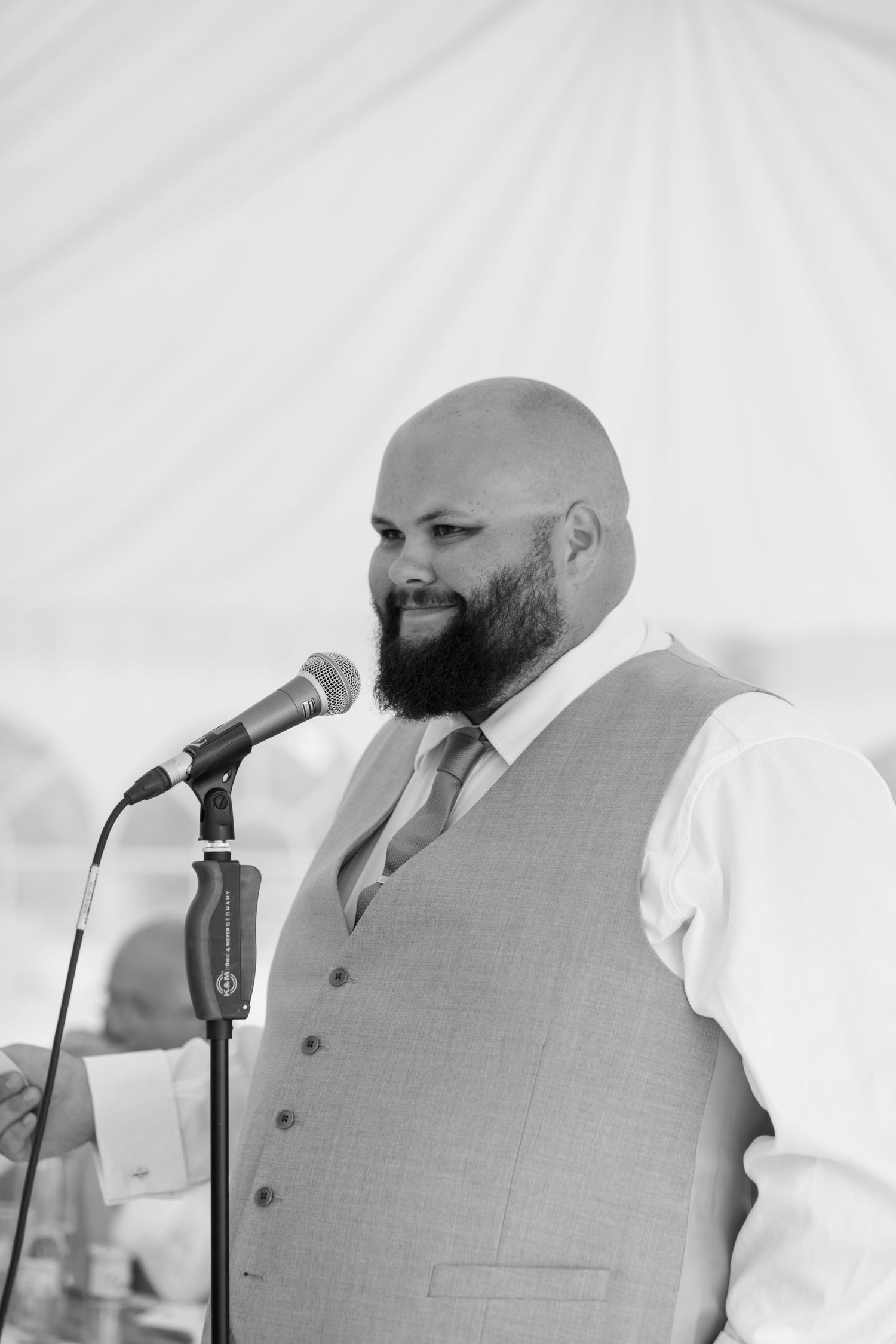 Black and White portrait of a Groom with a microphone giving his wedding speech.