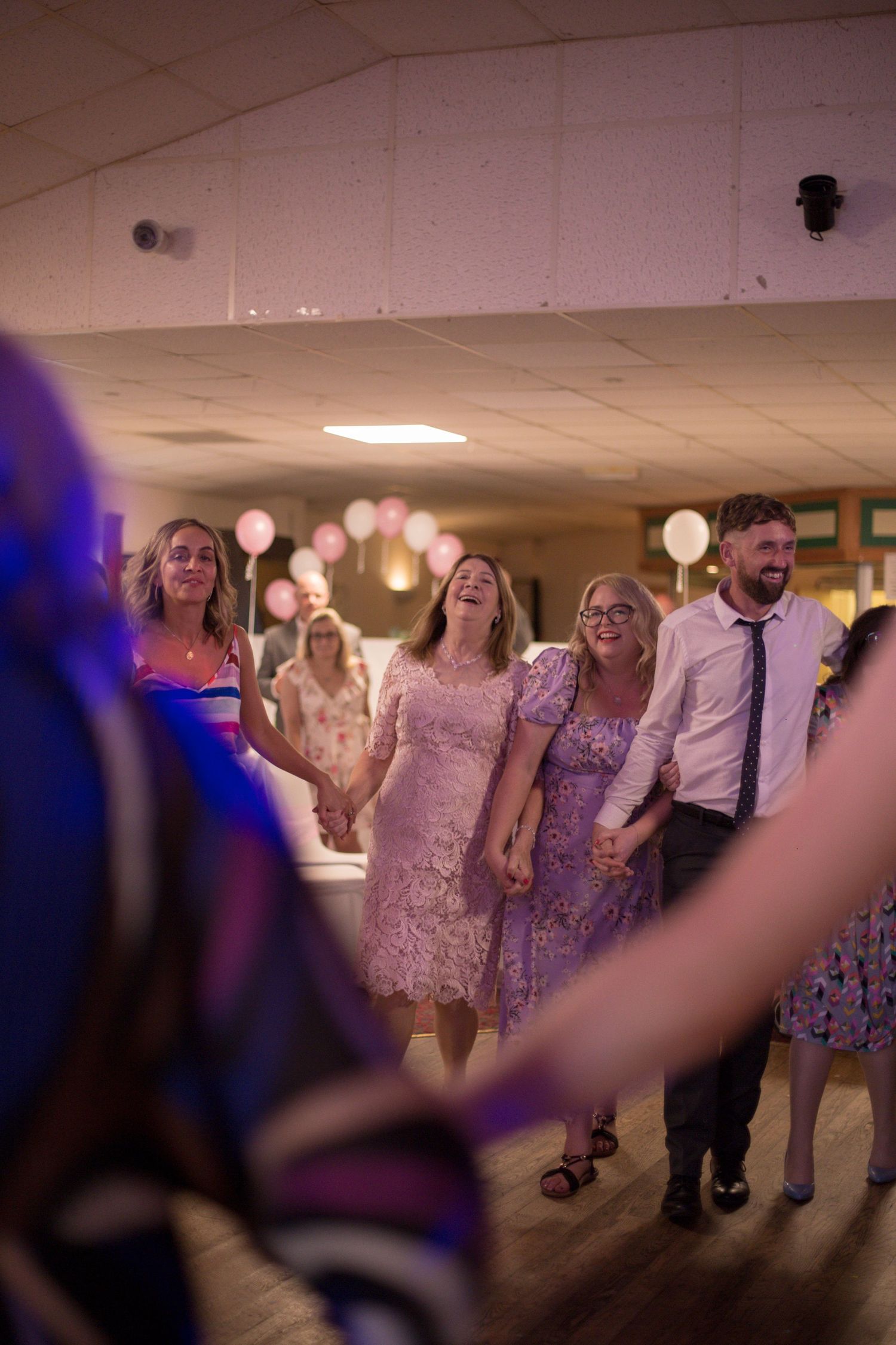 A dance circle formed on the dance floor, shot through the arms of two of the participants of the people opposite laughing