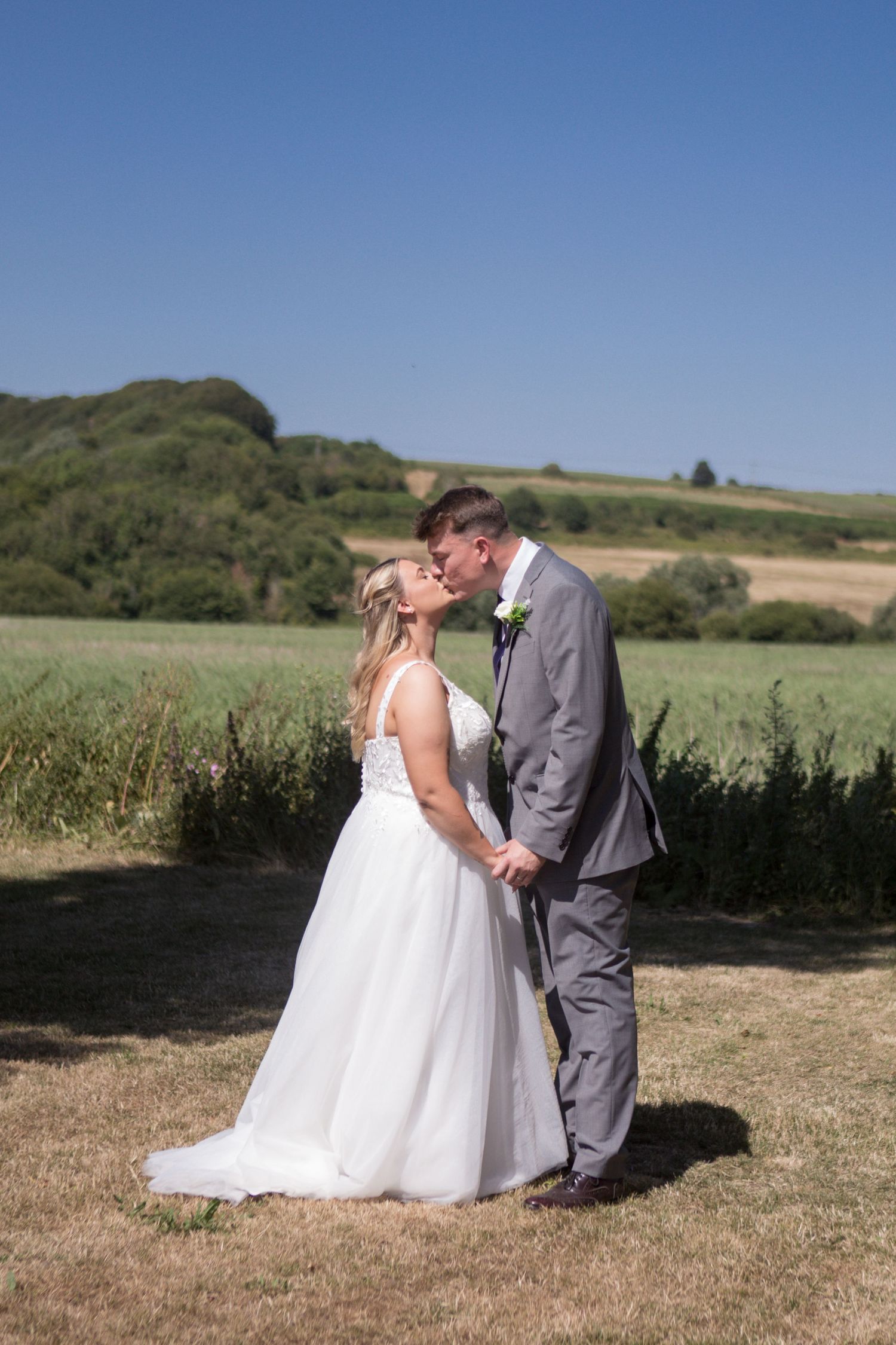 Bride and Groom share a kiss during a quiet moment in a sunlight field