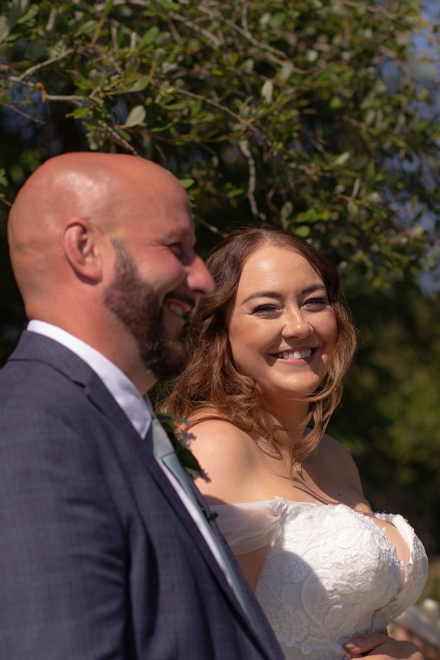 Bride laughing looking over at the groom in the middle of their ceremony