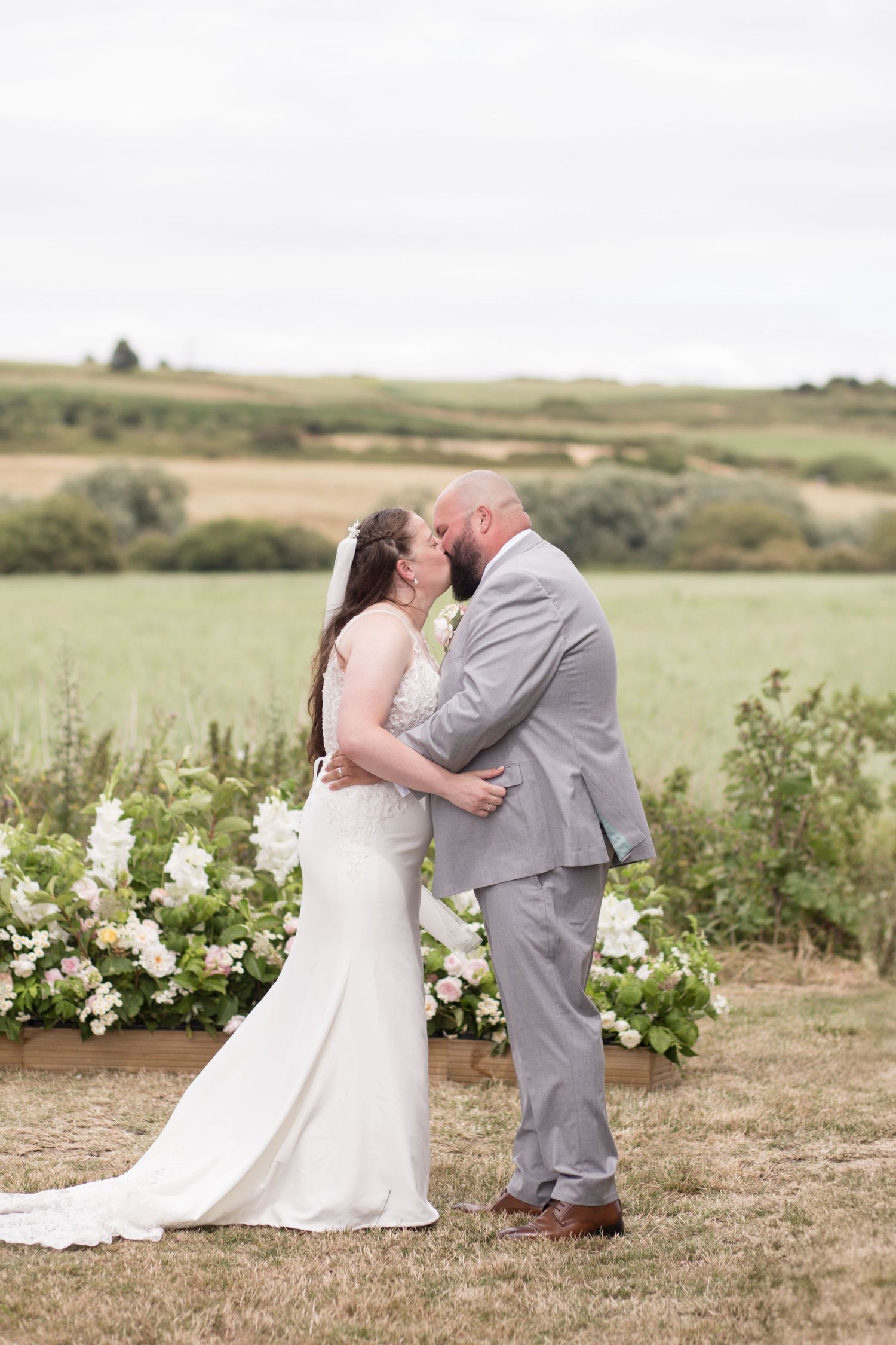 Bride and Groom share first kiss during their outside ceremony, surrounded by green fields and hills