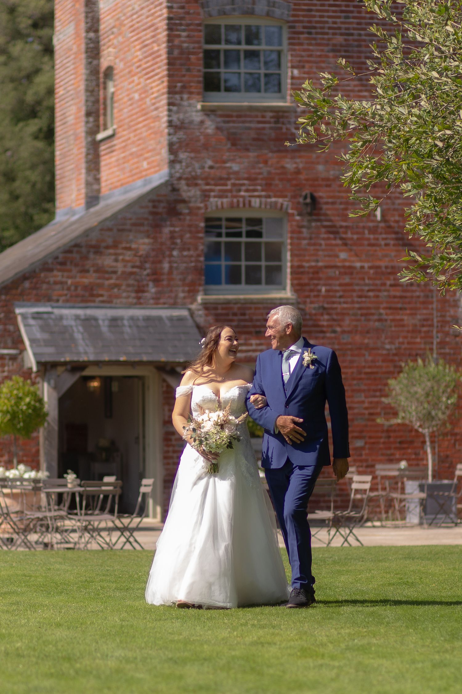 Bride and her father making their way across the field to the outdoor ceremony area at Sopley Mill