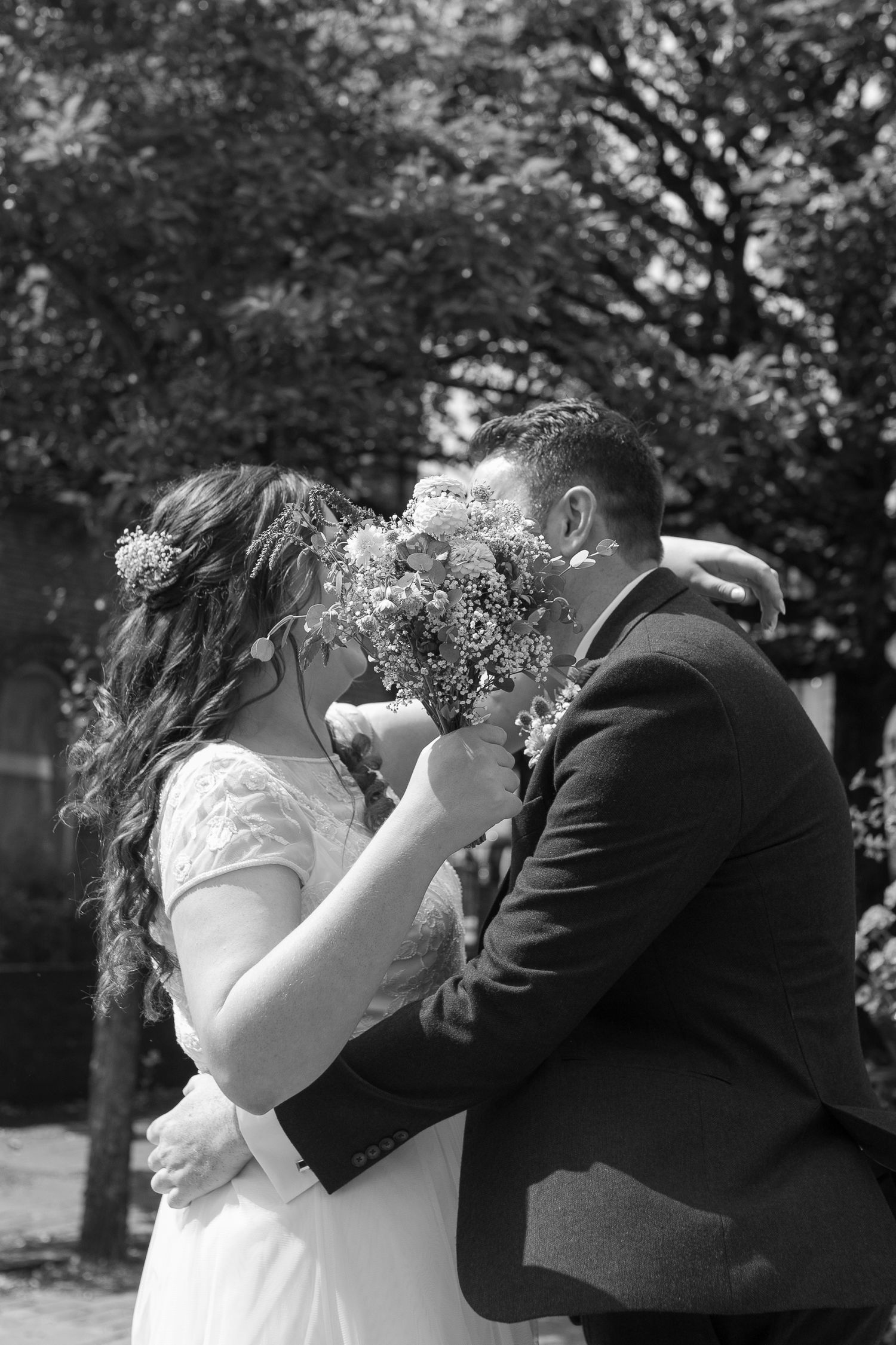 Bride and Groom share a kiss, hidden behind the bride's bouquet