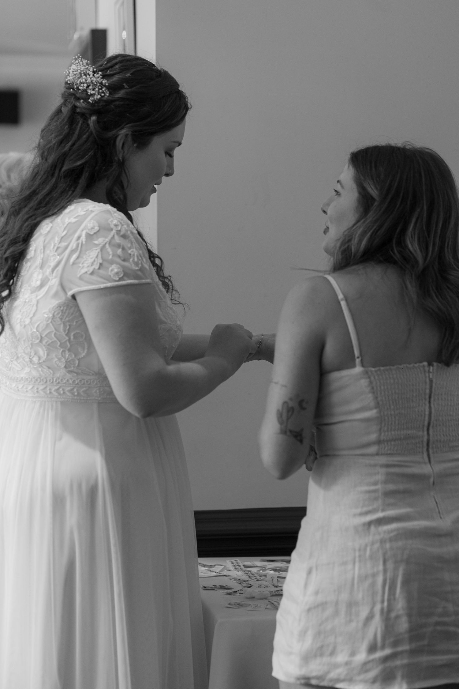 Bride and a friend stood huddled together as they put on temporary tattoos
