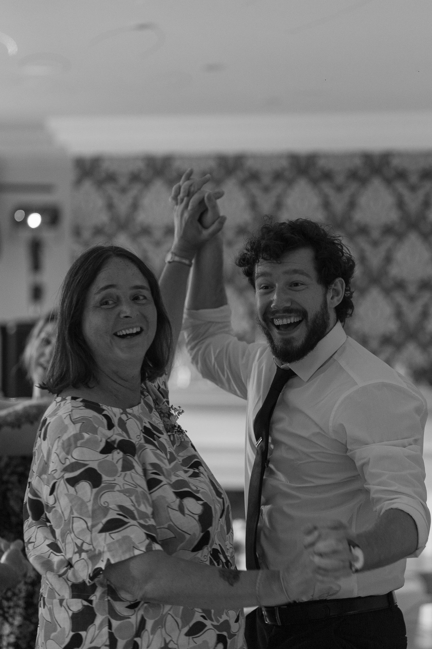 A man and woman pose for a photo. Smiles on their faces, their hands clasped together in the middle of their dance.