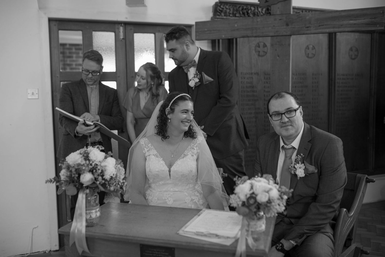 Bride and Groom sat sharing a quiet moment in the middle of their ceremony, as the vicar and their witnesses chat behind them