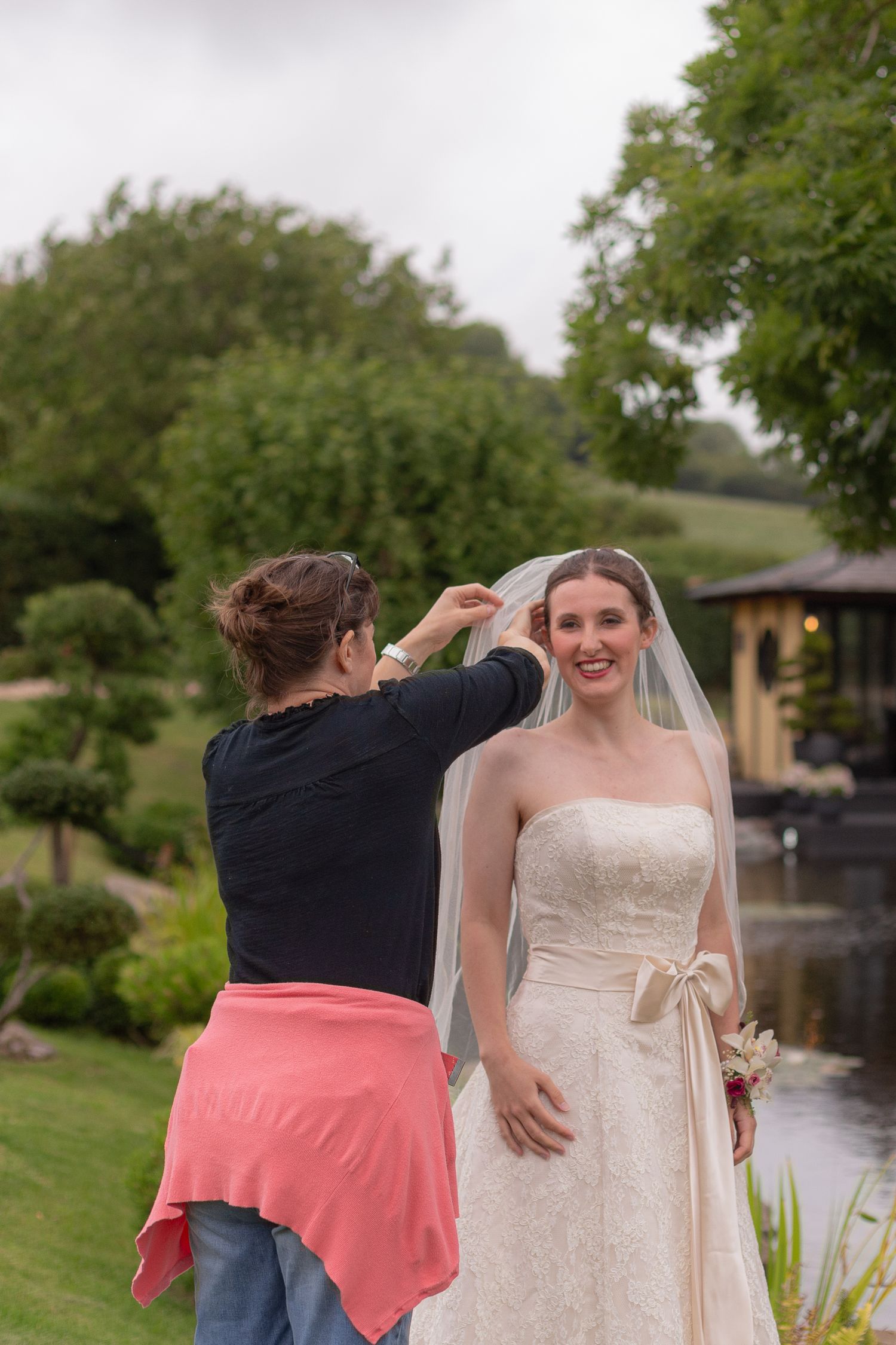 A make up artist helps a bride tuck her hair back behind her eye, settling her veil back over the top.