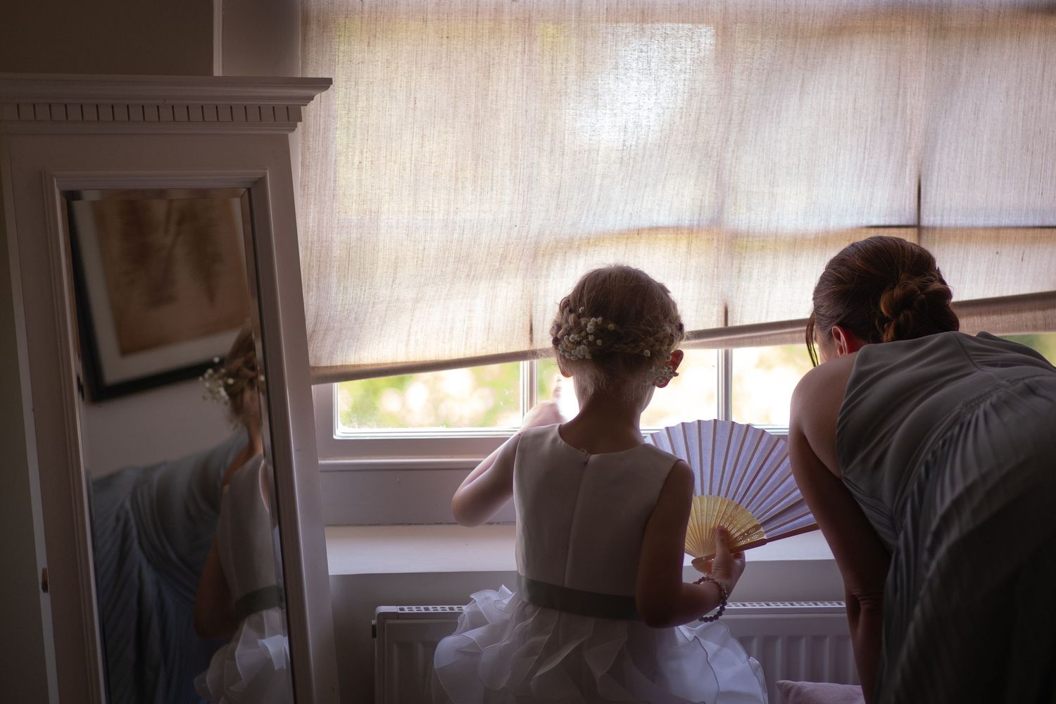 Bridesmaids and Flower girl sneaking a look out of the window as the other guests start to arrive