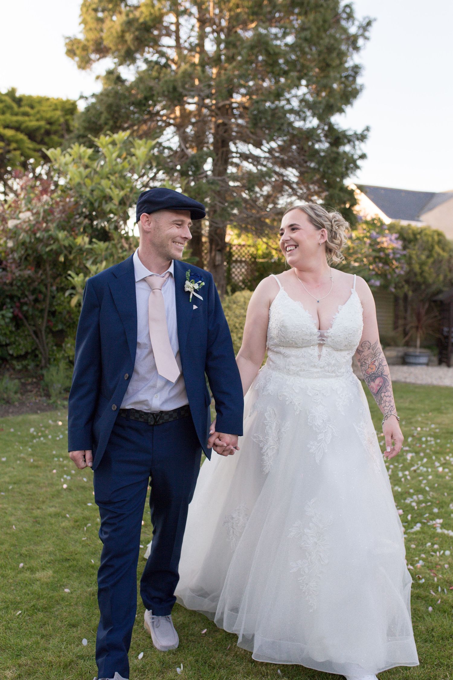Bride and Groom holding hands, smiling at each other and walking across the garden of the Hotel Rembrandt in Weymouth