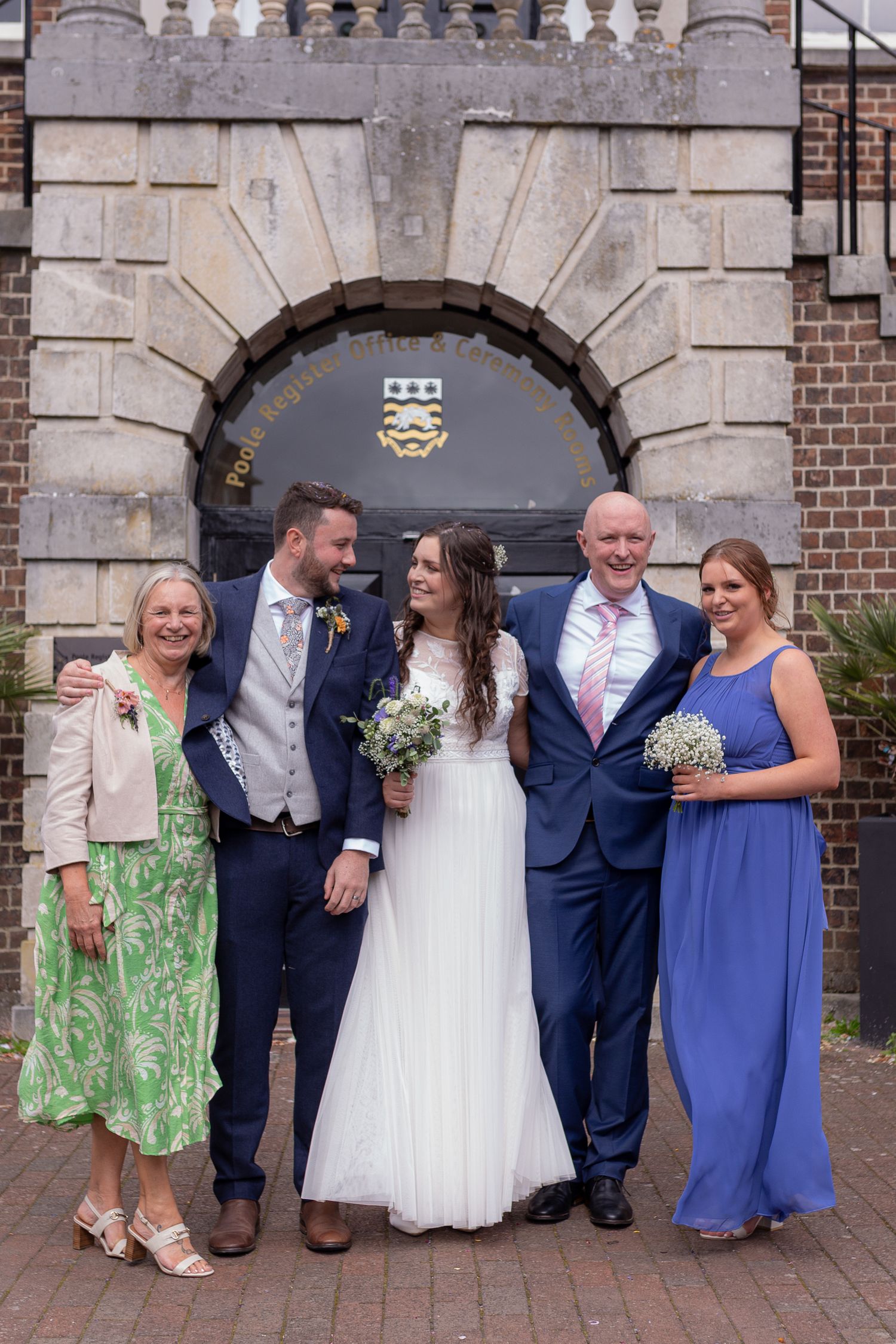 Bride's family smile to the camera, as the bride and groom get lost in each others eyes