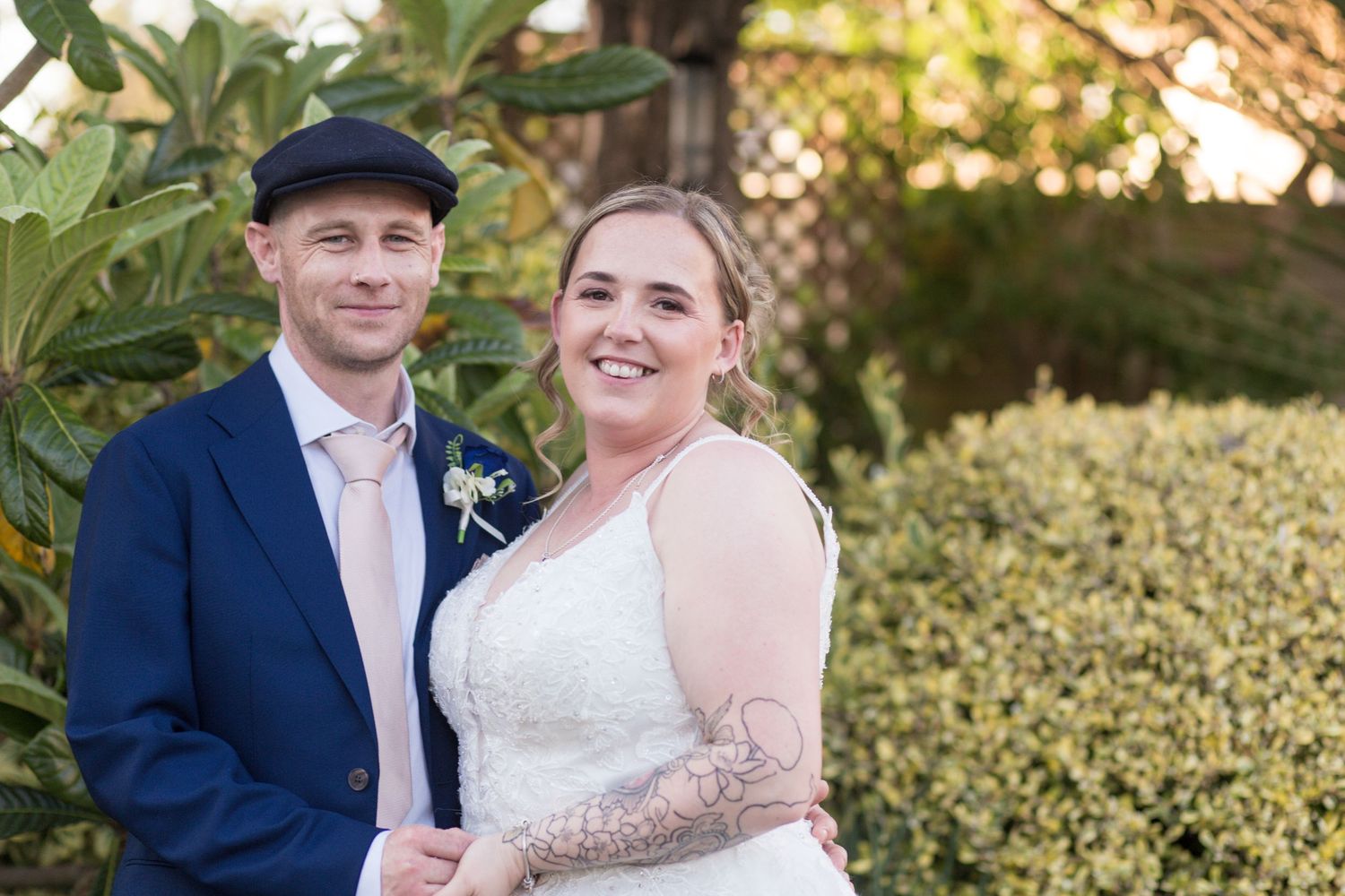 Close up of Bride and Groom smiling for a photo. Bodies angled together, hands held in the front.