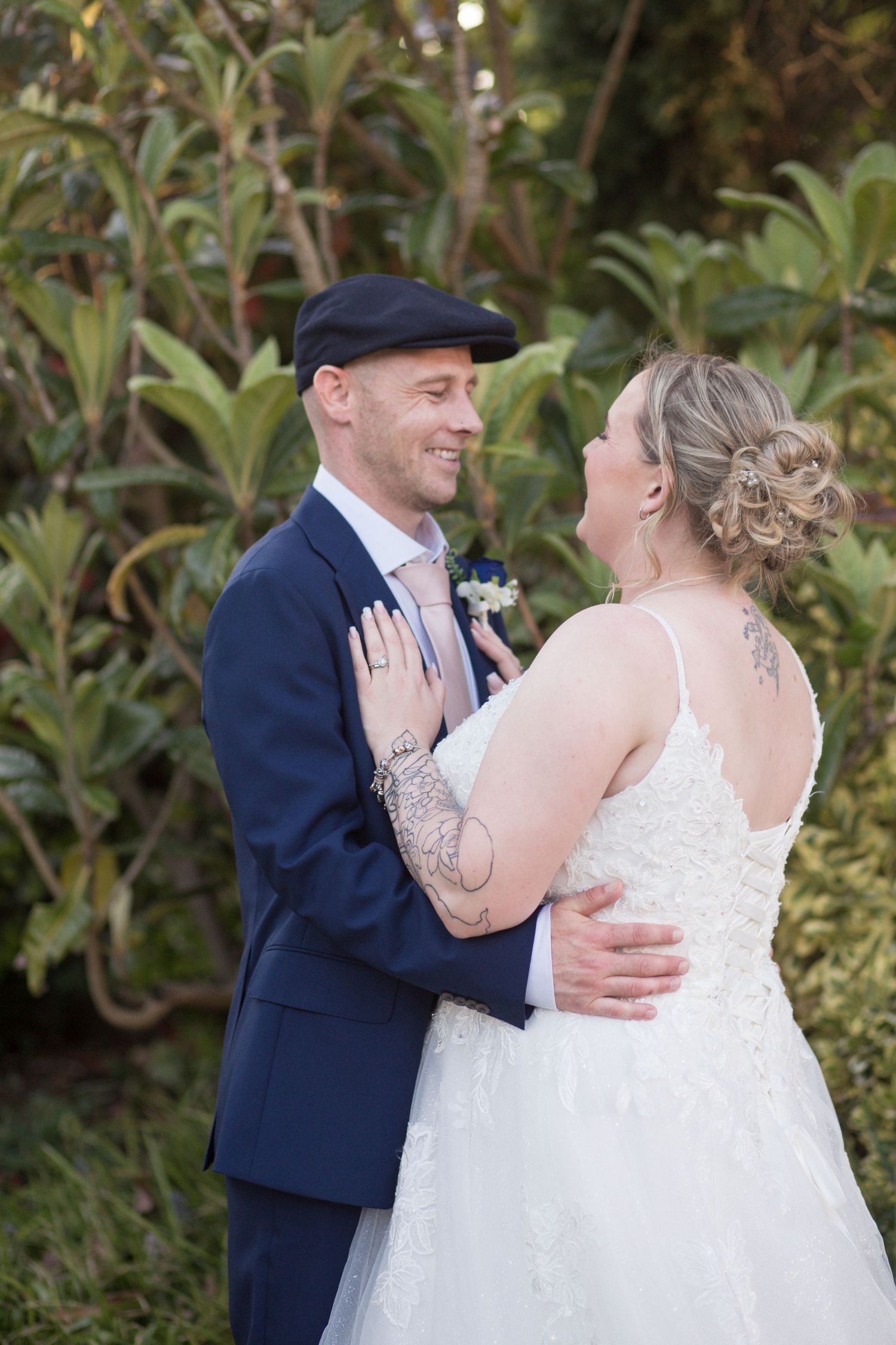 Bride and Groom wrapped in each others arms, smiling at each other in the gardens of the Hotel Rembrandt unaware of the camera