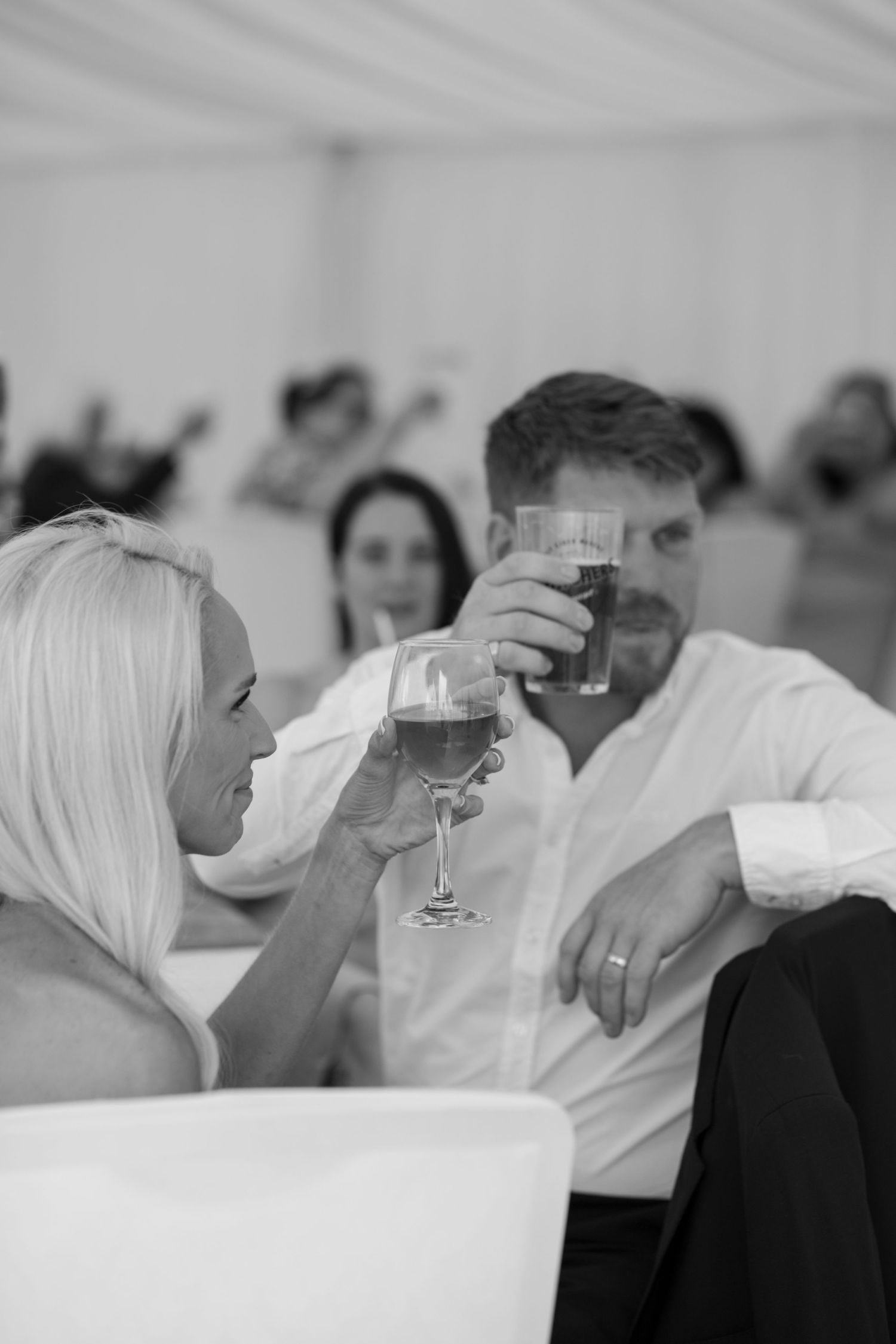 Two wedding guests raise a glass in toast to the Bride and Groom