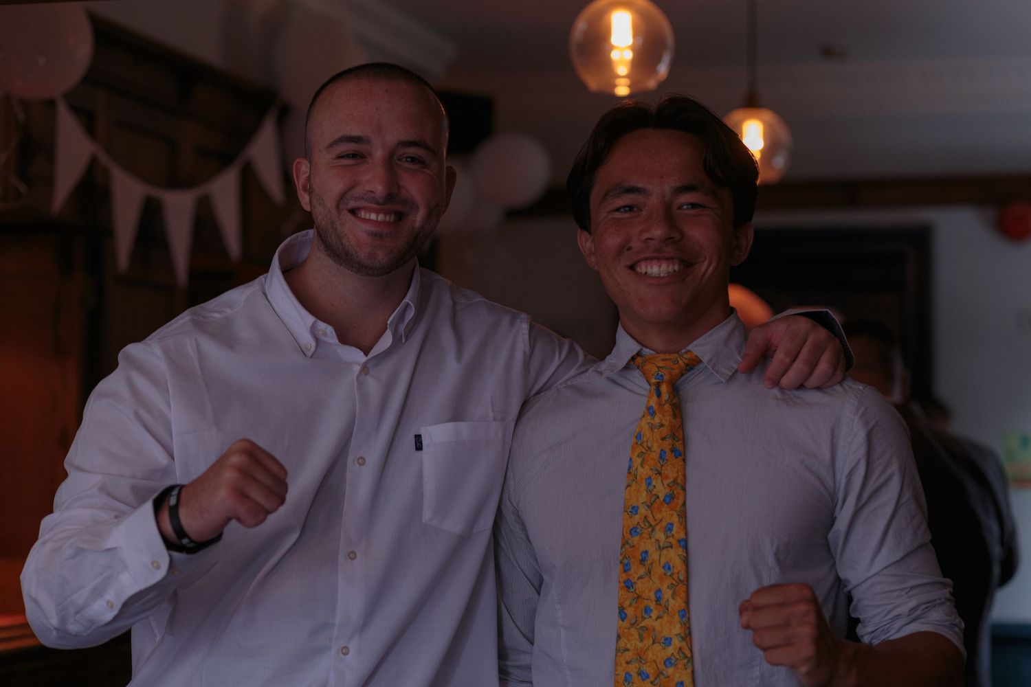 Two men stood smiling with their arms round each others shoulders.