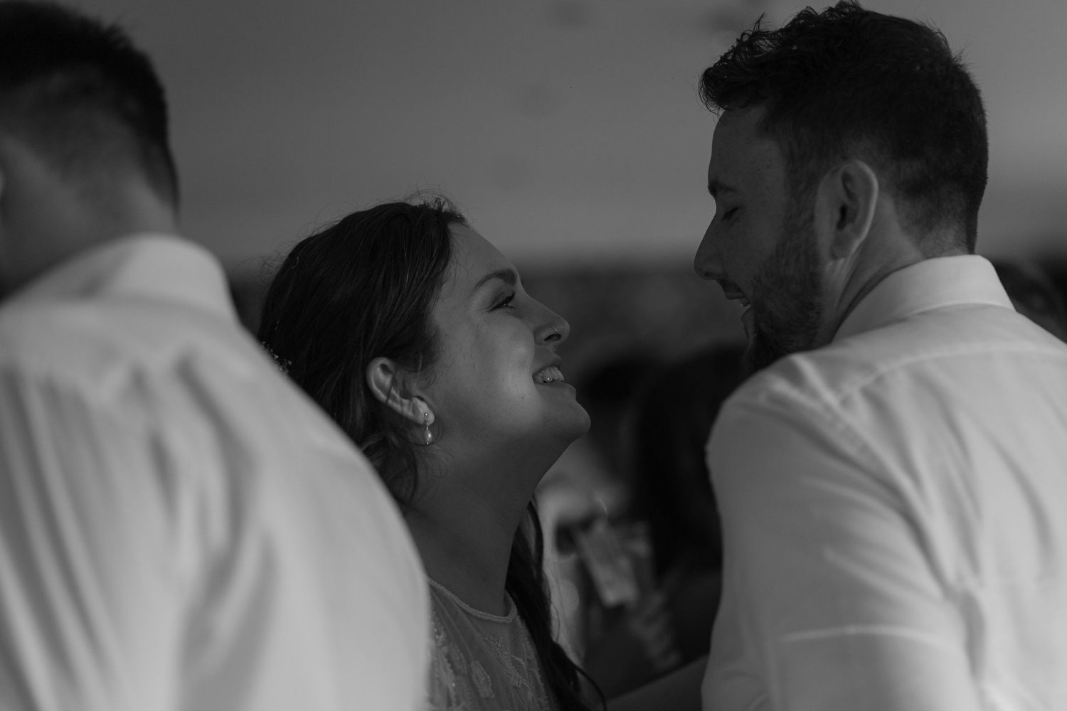 Bride and groom looking into each others eyes, a quiet moment between them in the middle of a packed dancefloor.
