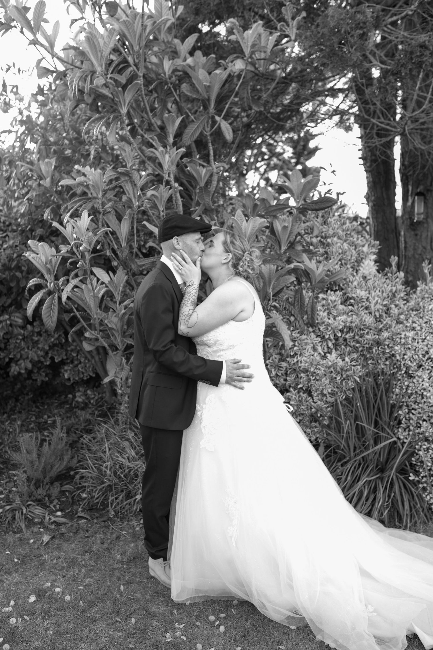 Black and White photo of a Bride and Groom sharing a kiss in the gardens of the Hotel Rembrandt