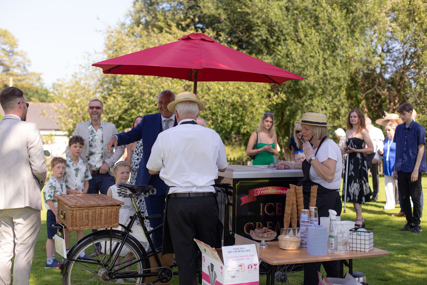 Wedding guests crowd round an Ice Cream stand during this outdoor wedding during a heatwave