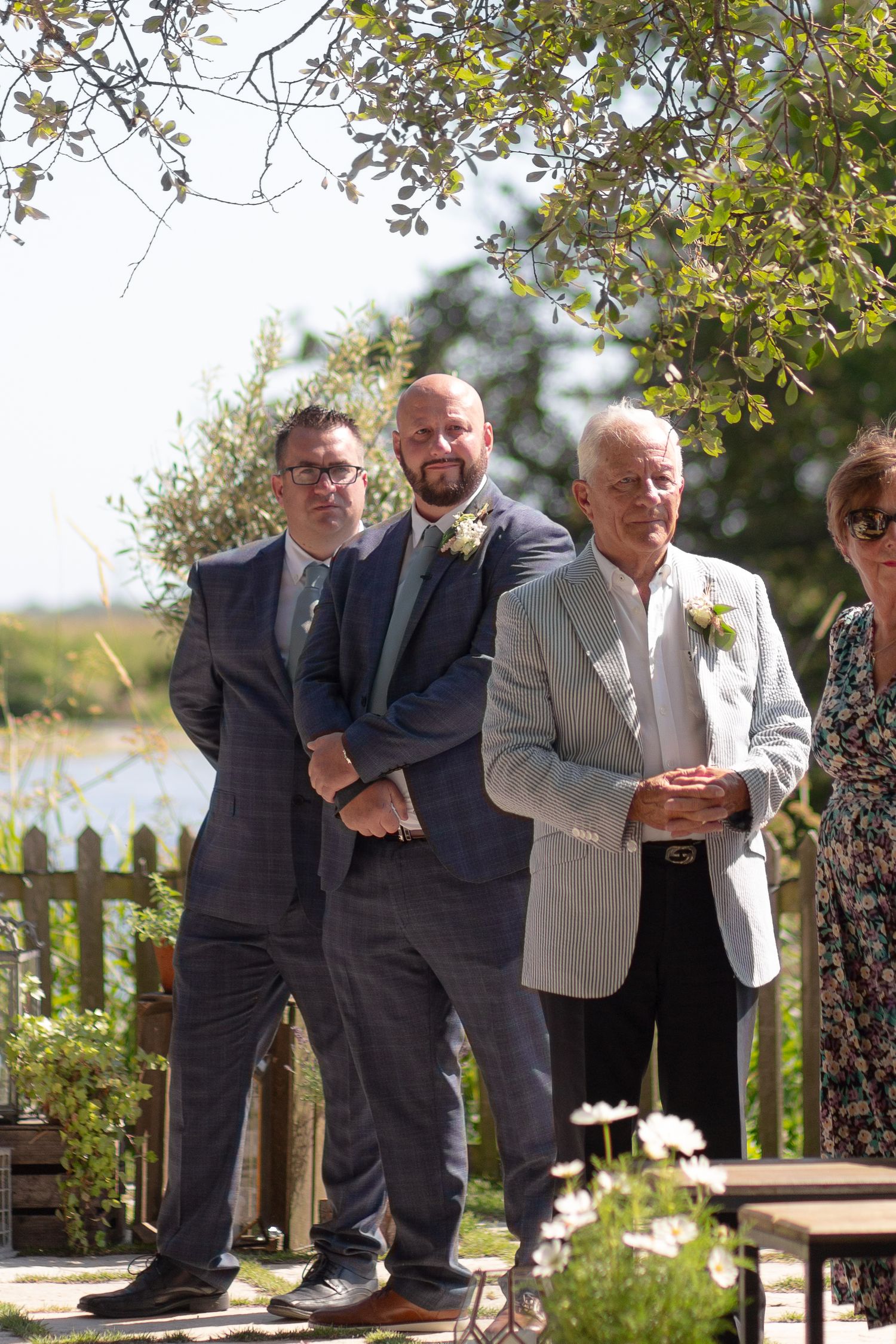 Groom, Best Man and Groom's Father wait at the end of the aisle for the Bride
