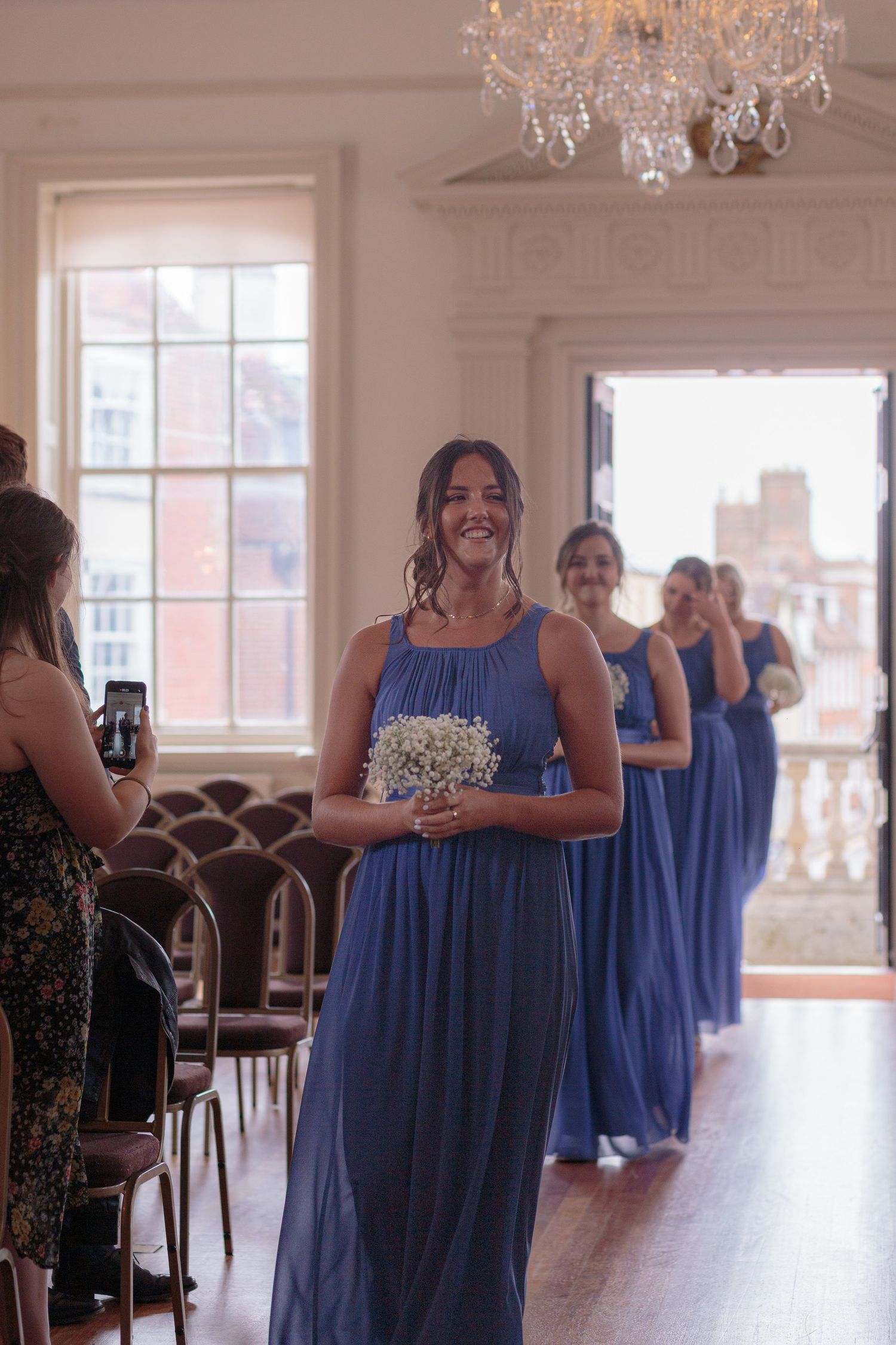 A row of bridesmaids dressed in blue enter the ceremony space at the guildhall in Poole