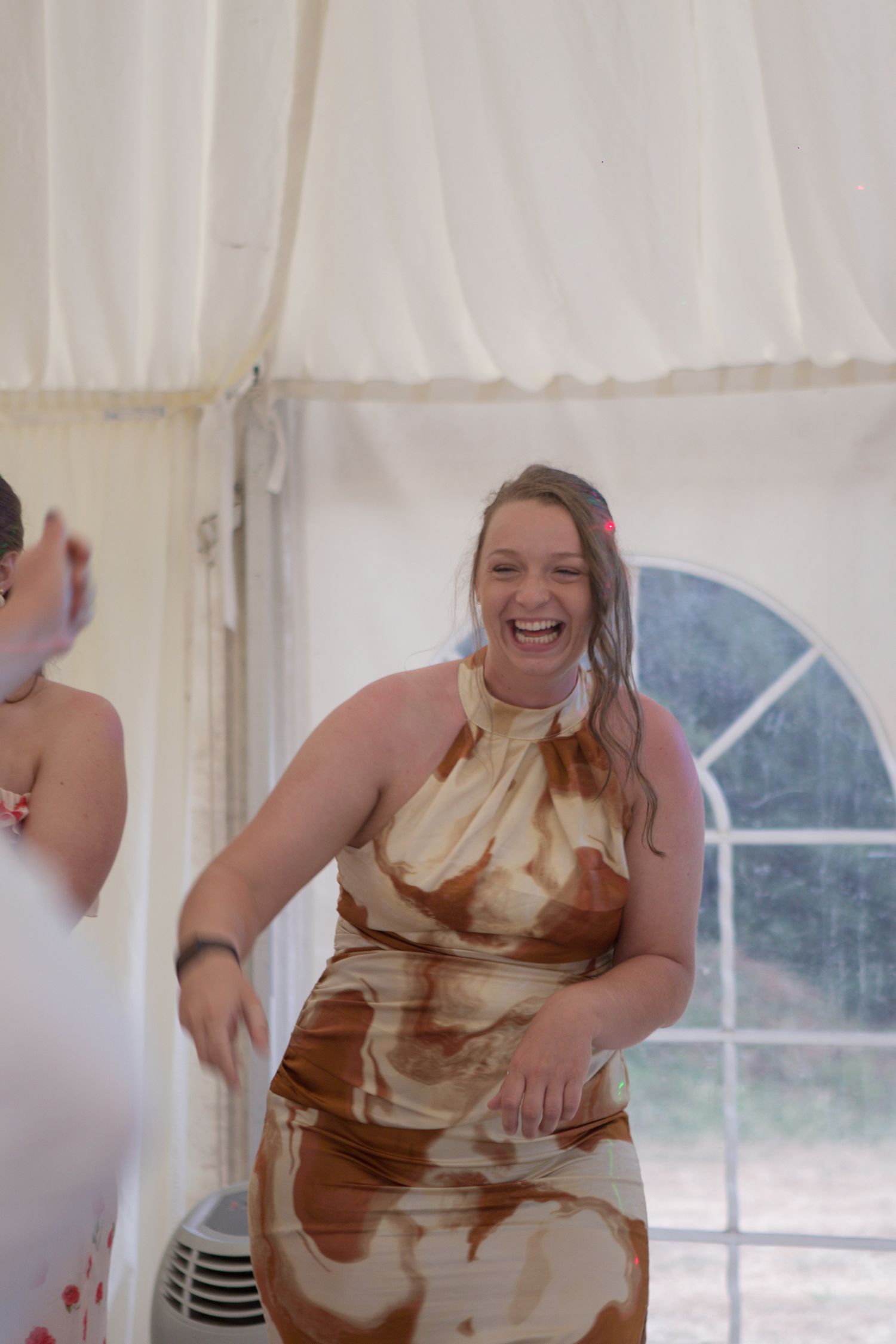A female wedding guest laughing at someone on the dancefloor