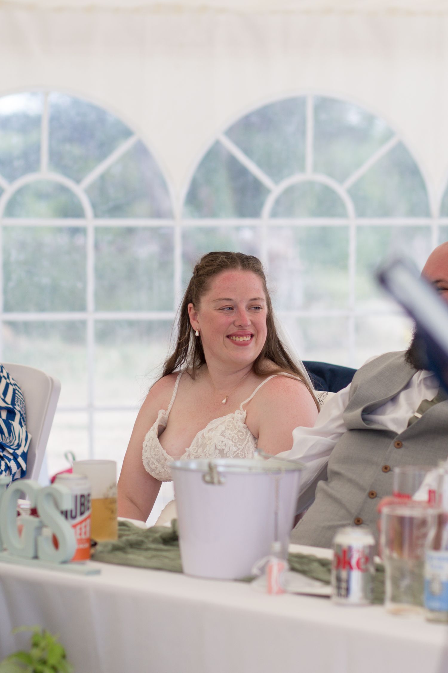 Portrait of a Bride smiling at her Groom whilst the Best Man gives a speech.