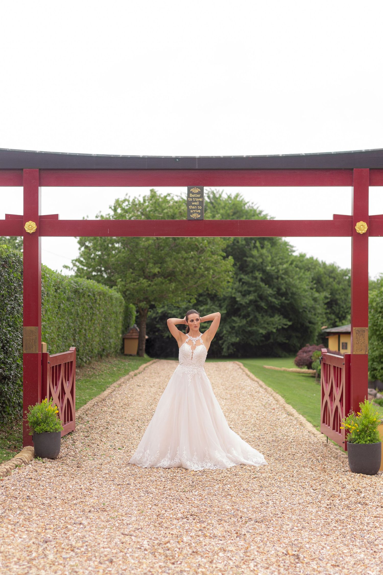 A bride poses for a photo underneath a Japanese style torii gate.
