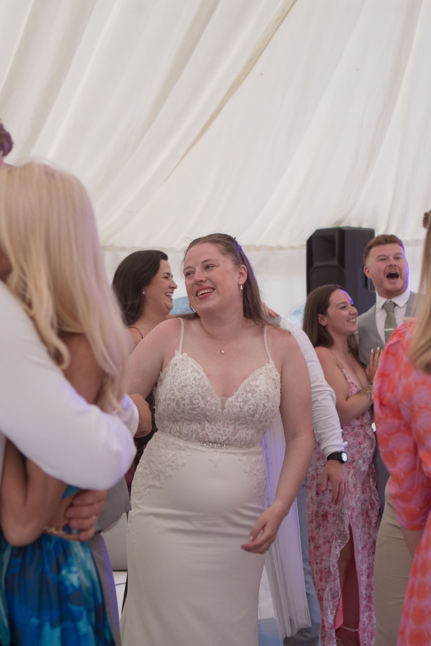 A photo of a bride surrounded by her guests in the middle of the dancefloor.