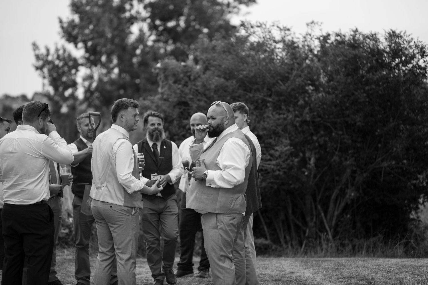 Groom and his groomsmen gathered around to smoke a cigar in the grounds of the weymouth rugby club