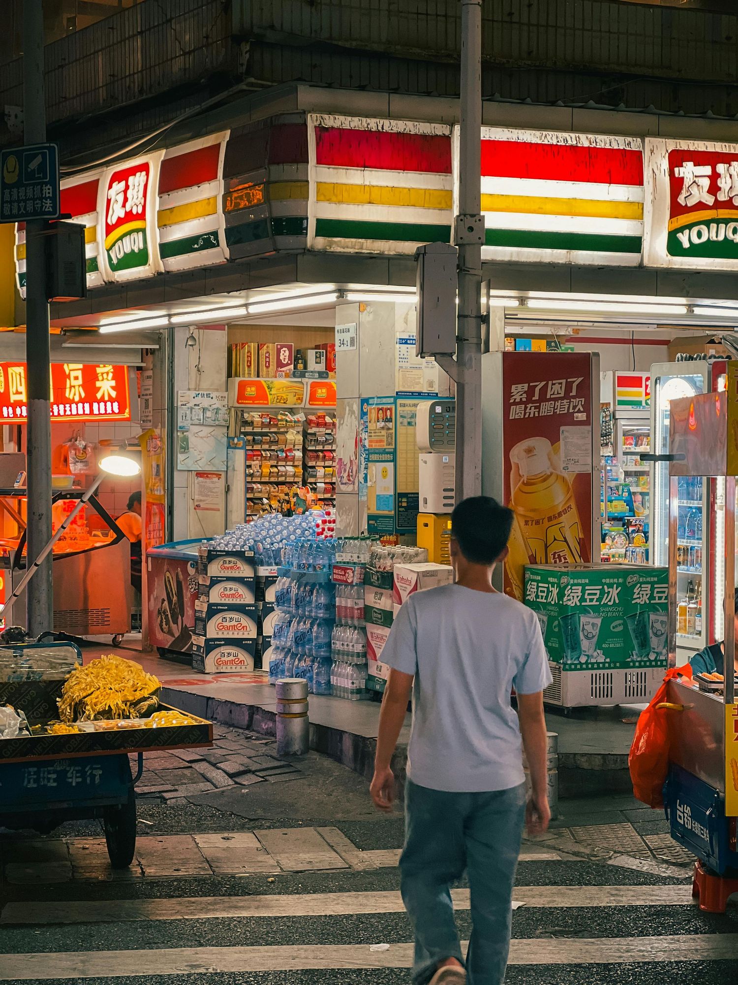 Illuminated convenience store exterior at night with neon signs and displays.