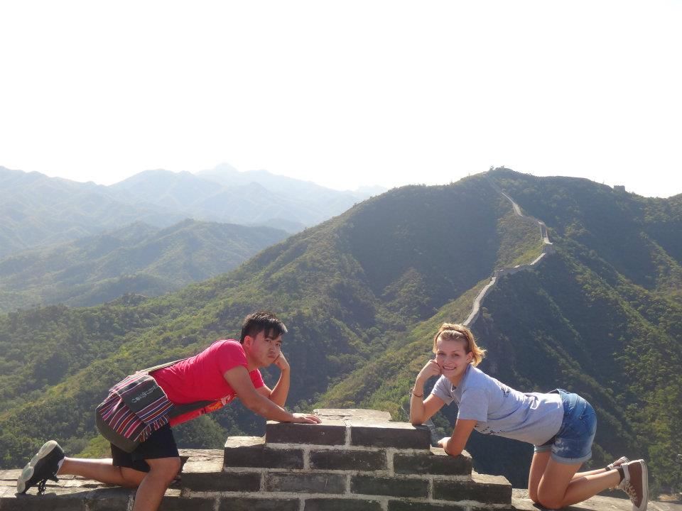 People doing planks in a line along the Great Wall of China with mountains in the background.