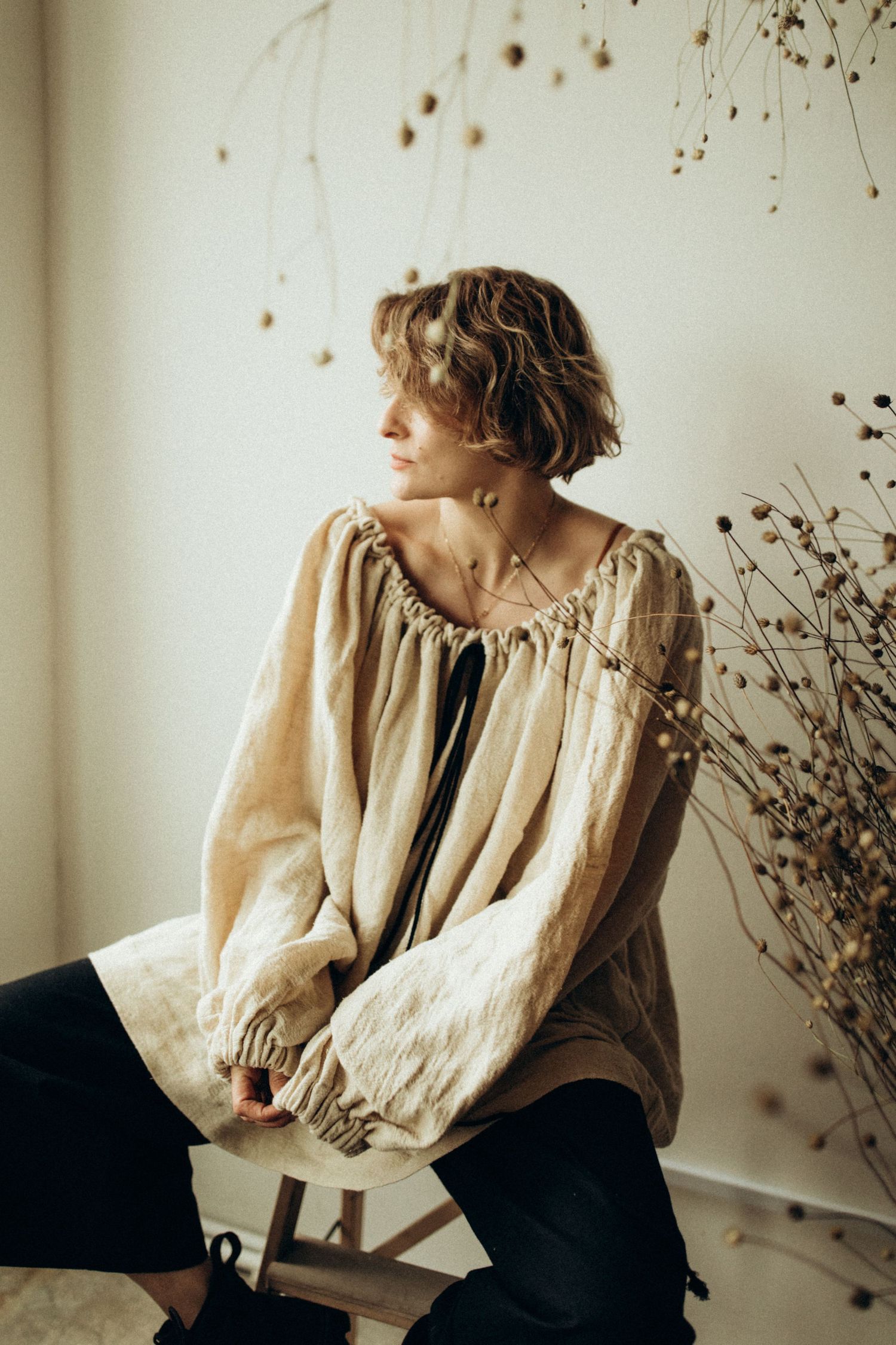 Vintage-inspired fashion portraits featuring cream blouse and dark pants against minimal backdrop.