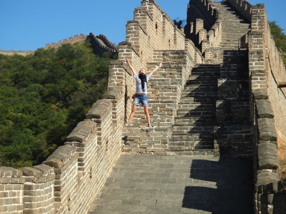 Ancient stone steps and walls of the Great Wall of China stretching across mountainous terrain.
