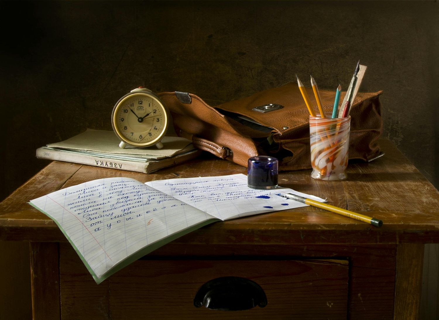 Vintage study desk with writing materials, clock, and handwritten notes in warm lighting.