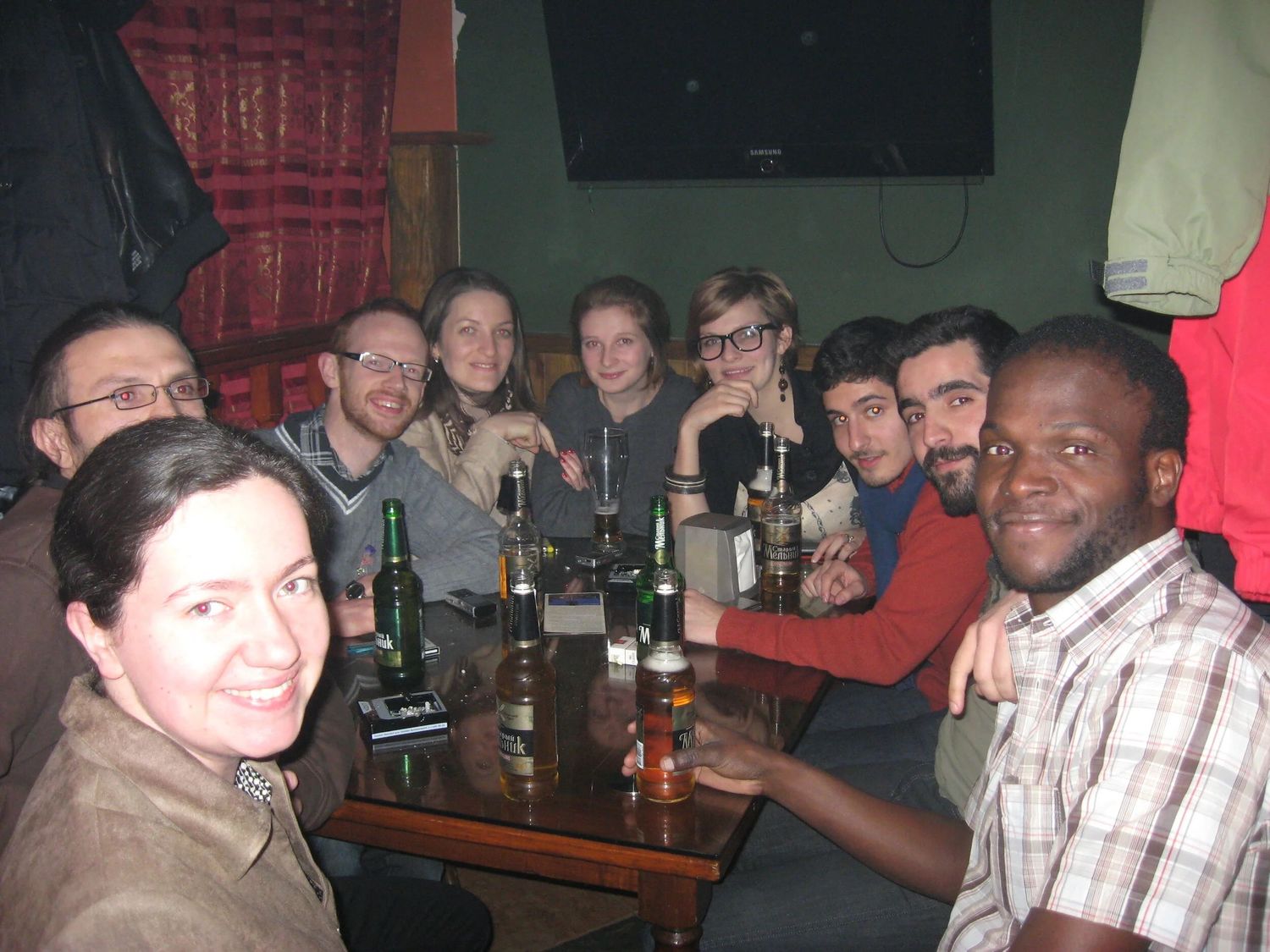 Friends gathered at a dimly lit bar or pub enjoying drinks and conversation.