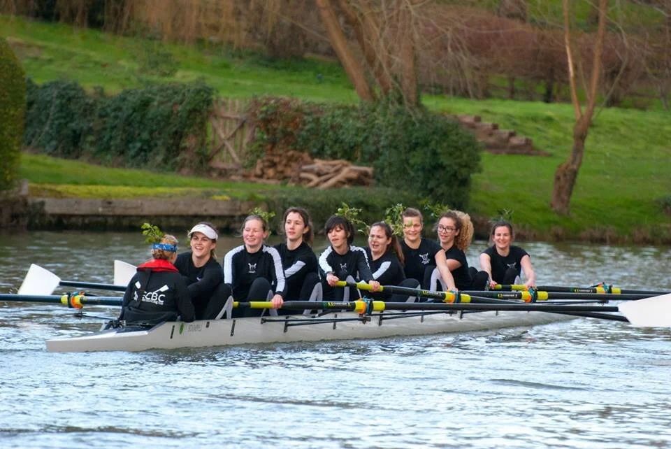 Rowing team practicing on calm waters with multiple boats in formation.