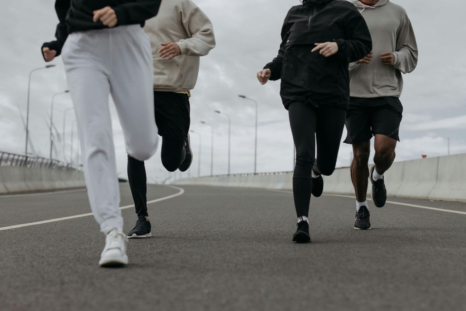 Group of runners exercising together on a concrete road on an overcast day.