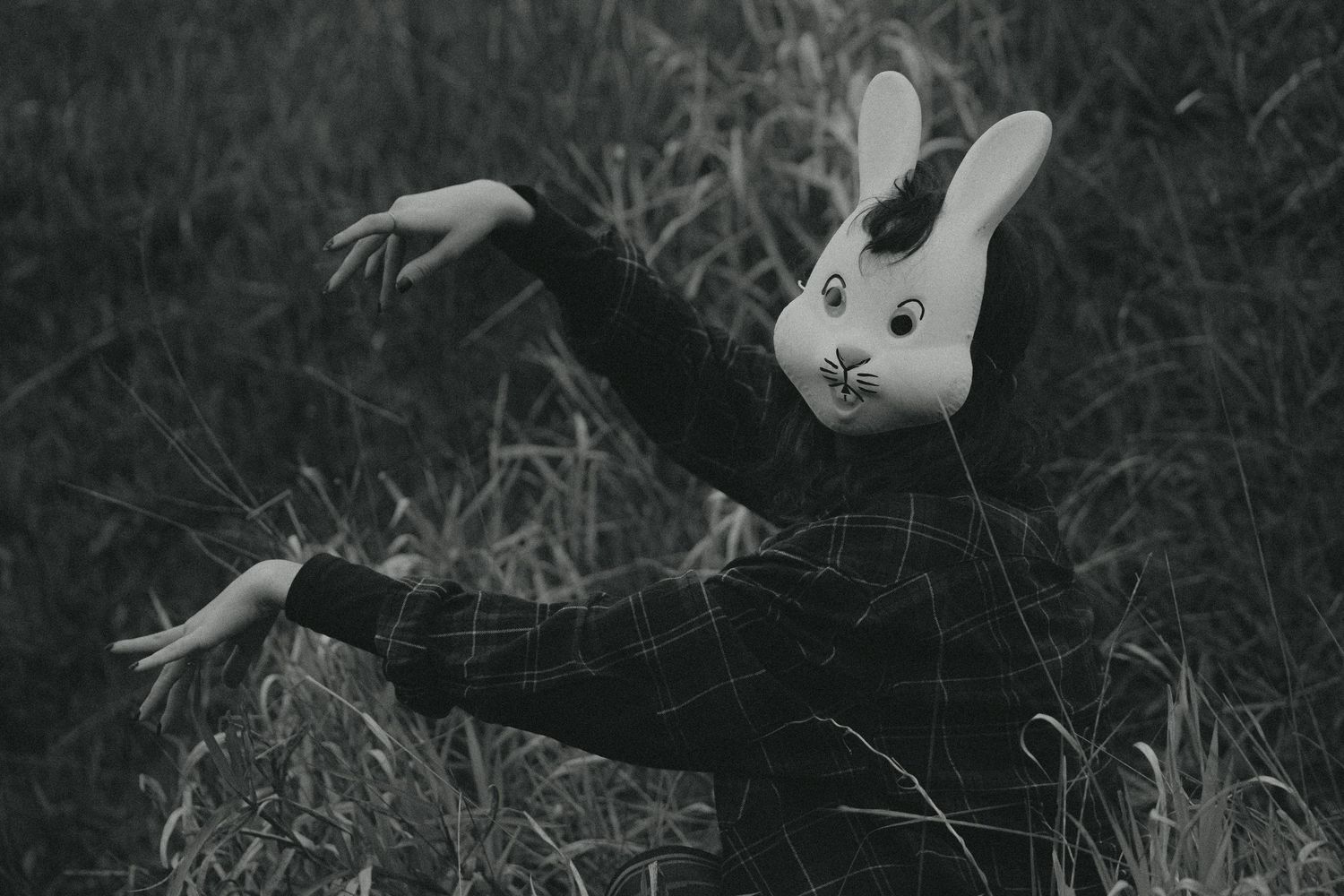 Black and white close-up of a small rabbit in grass.