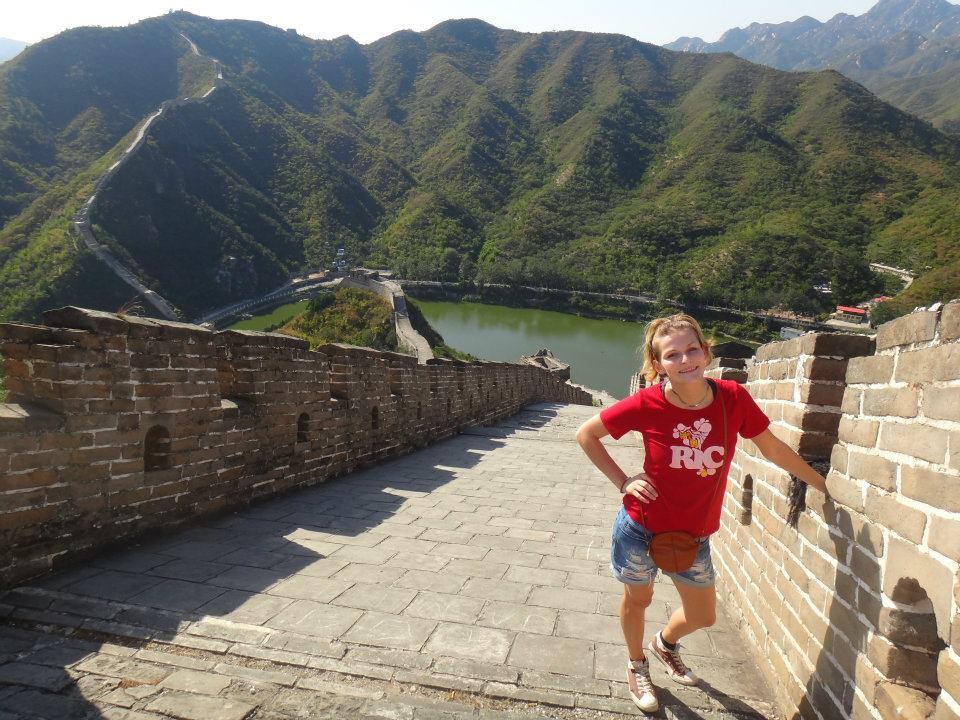 Panoramic view of the Great Wall winding through green mountains under blue sky.
