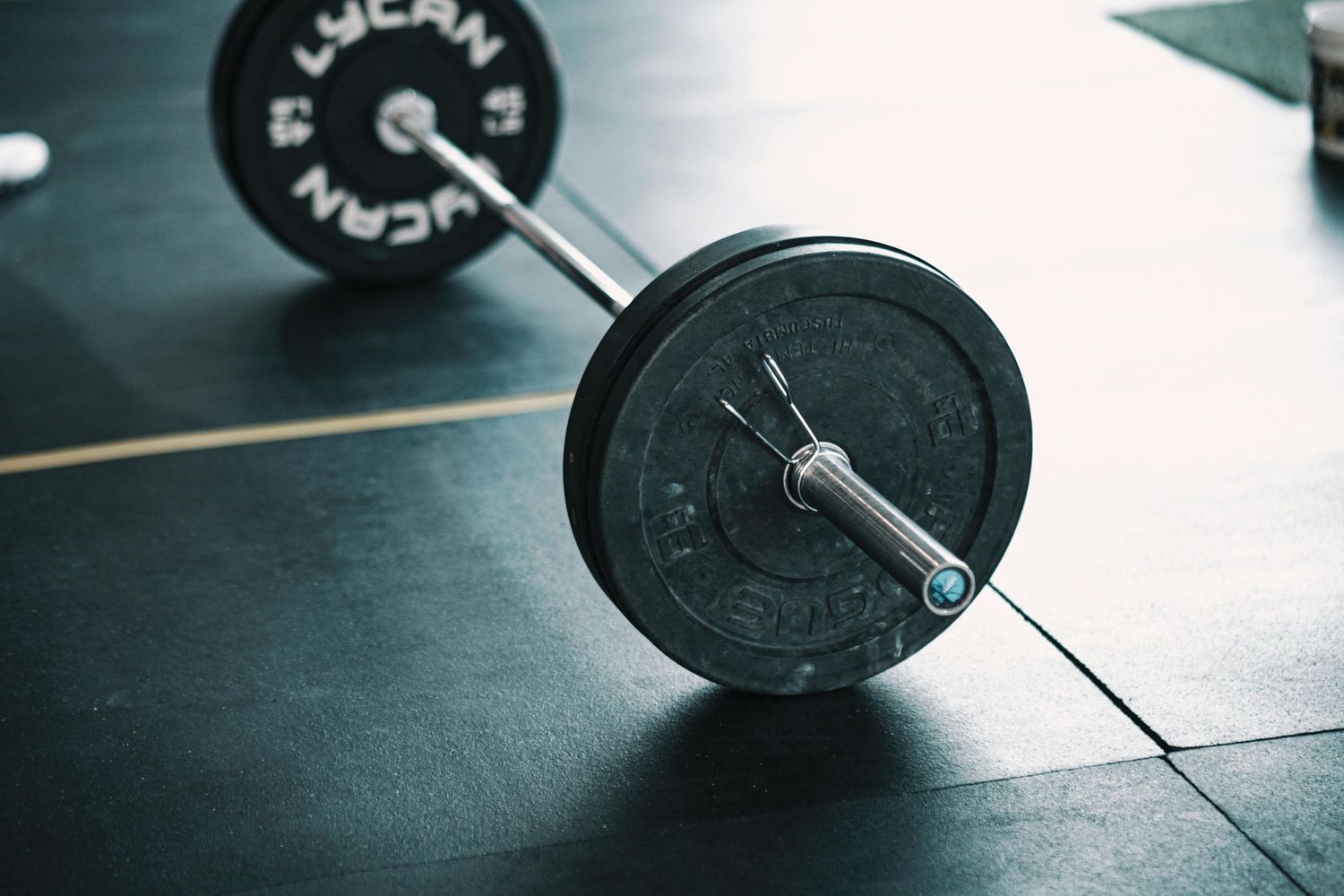Close-up shots of black weightlifting barbells and plates on a dark surface.